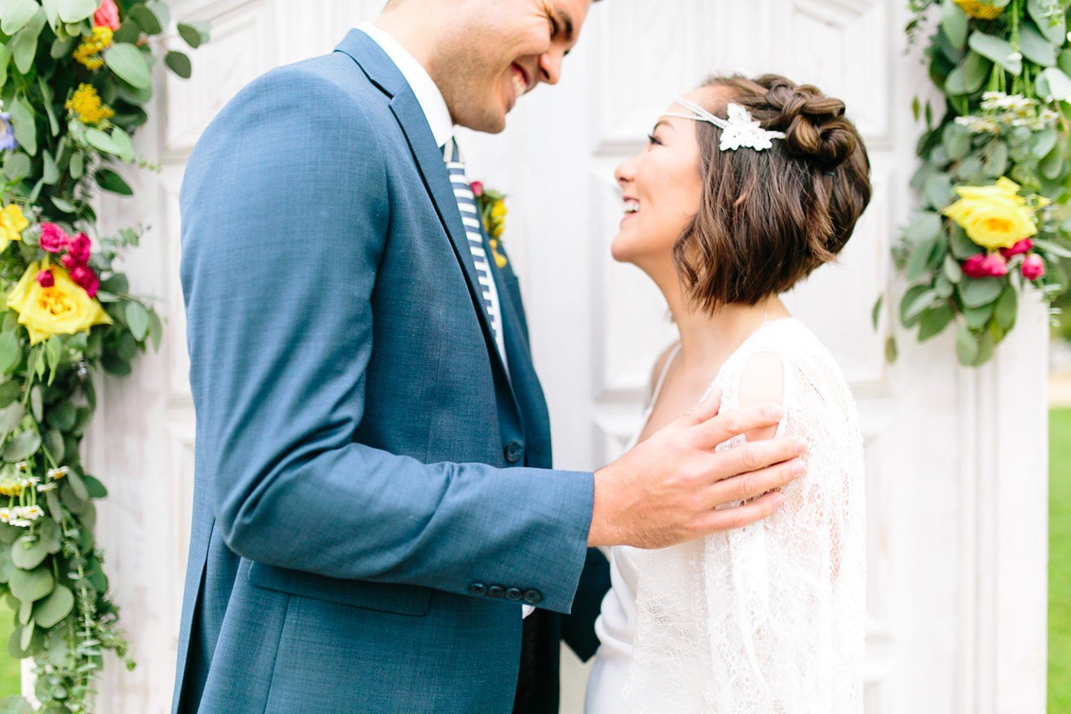A bride and groom are standing next to each other and looking at each other.