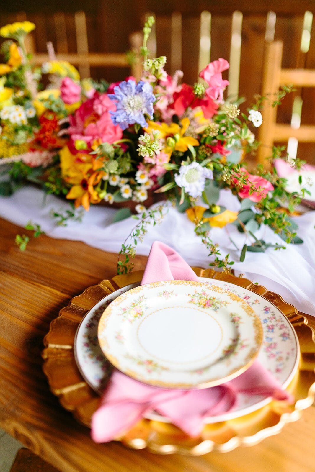 A table with plates and a vase of flowers on it.