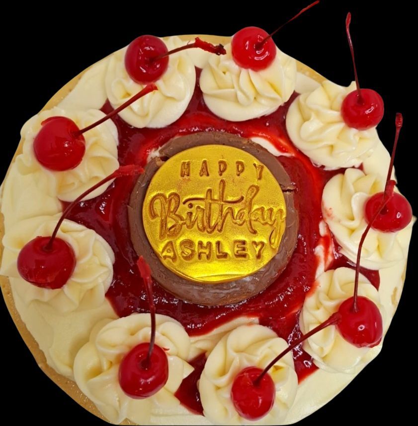 A birthday cake for ashley is decorated with cherries and whipped cream