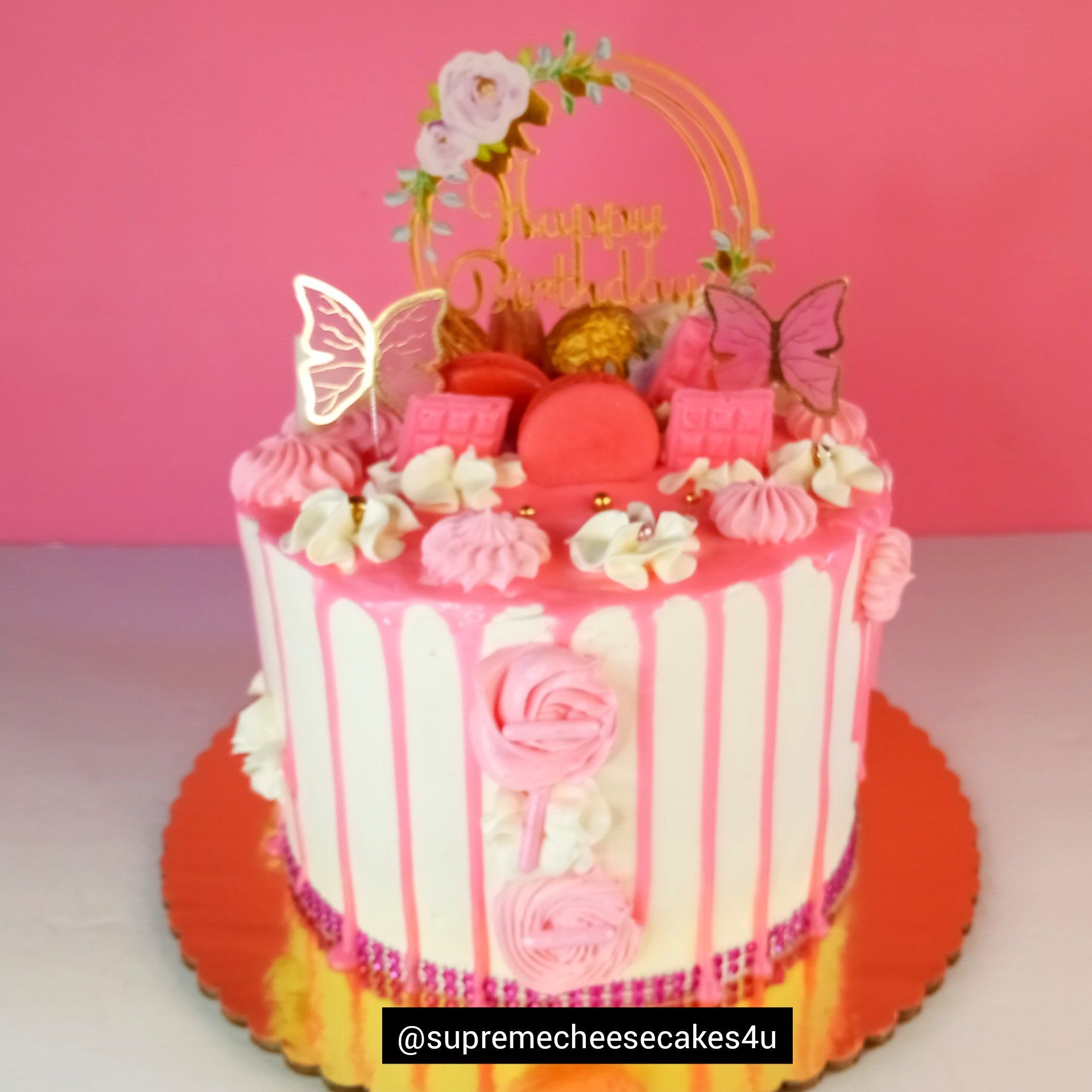 A pink and white cake with flowers and butterflies on it