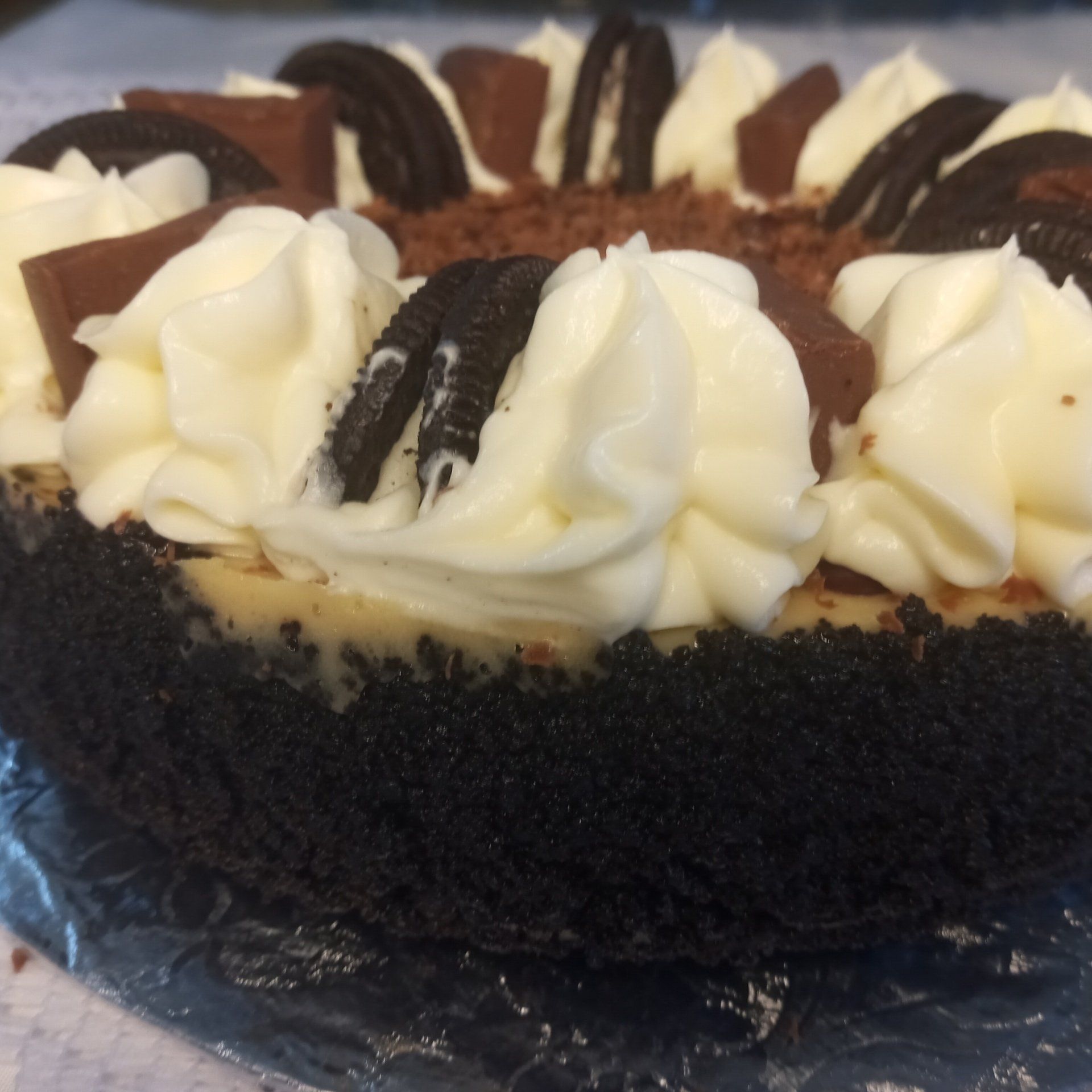 A chocolate cheesecake with whipped cream and oreos on top
