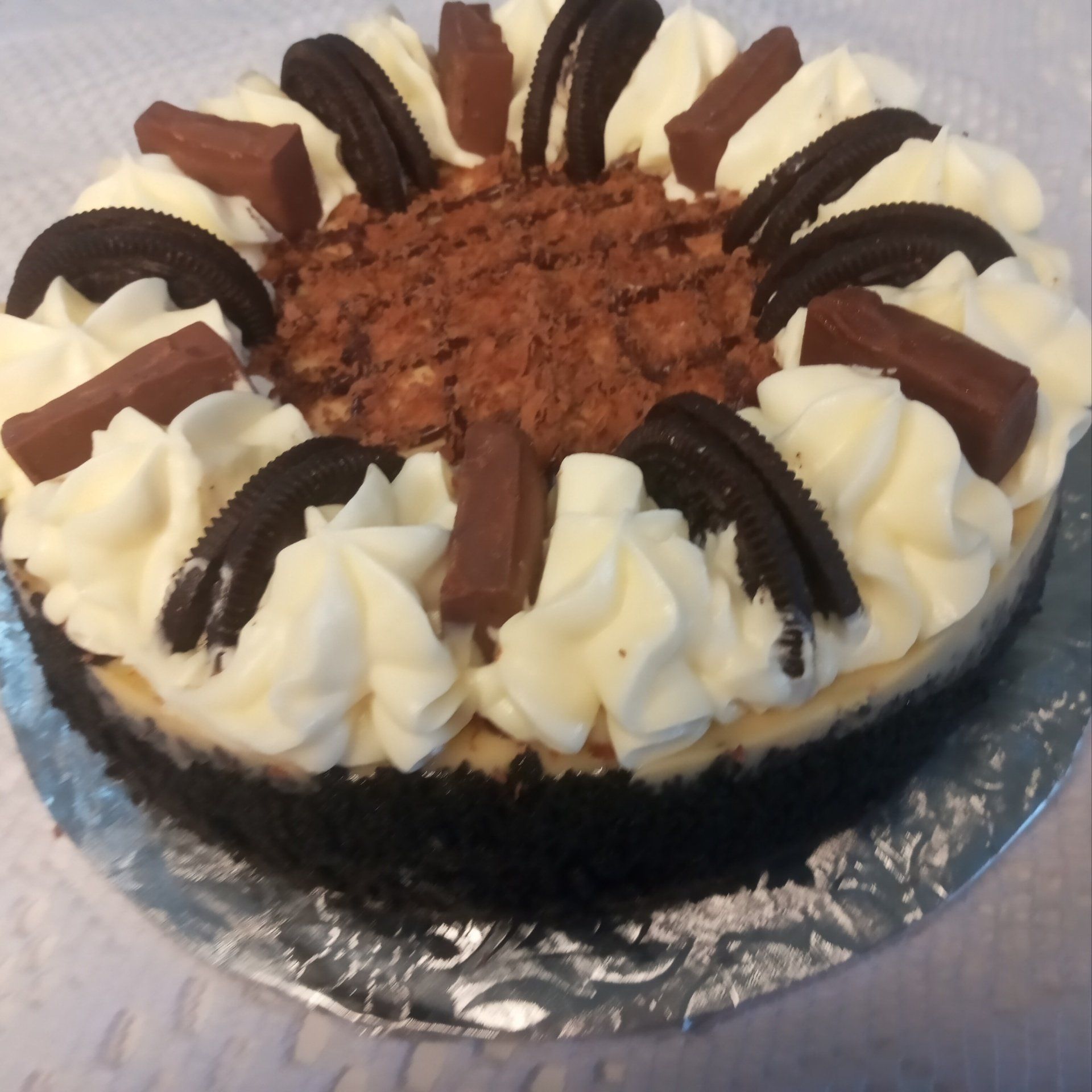 A chocolate cheesecake with whipped cream and oreos on top