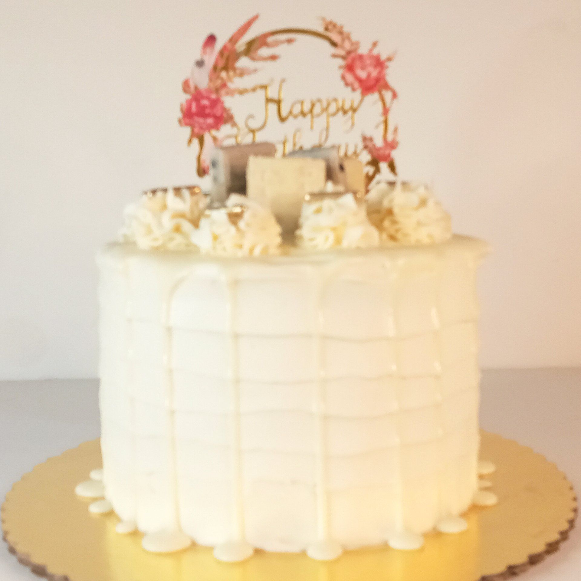 A white cake with a happy birthday topper on top