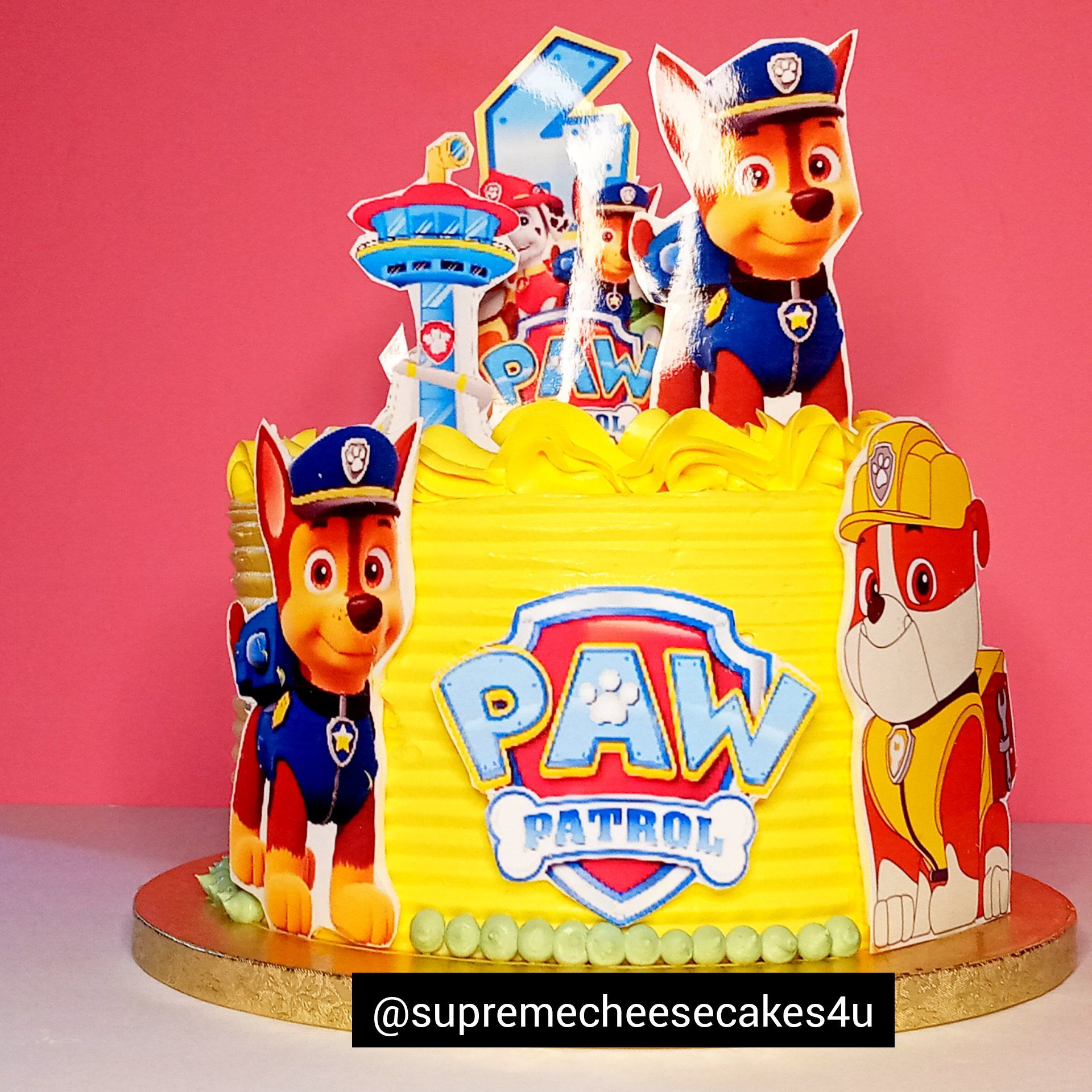 A yellow cake with paw patrol characters on top of it.