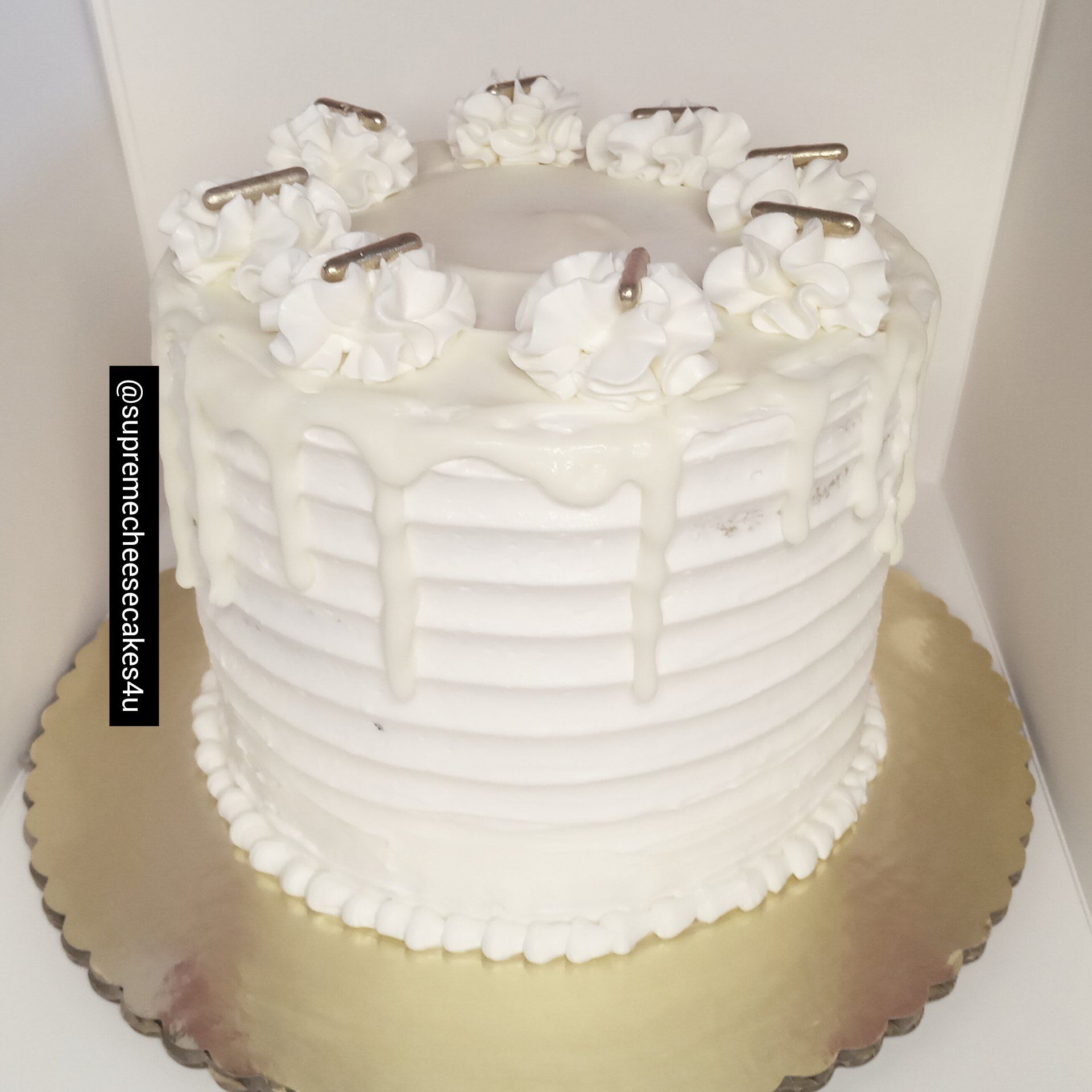 A white cake with whipped cream drips on it