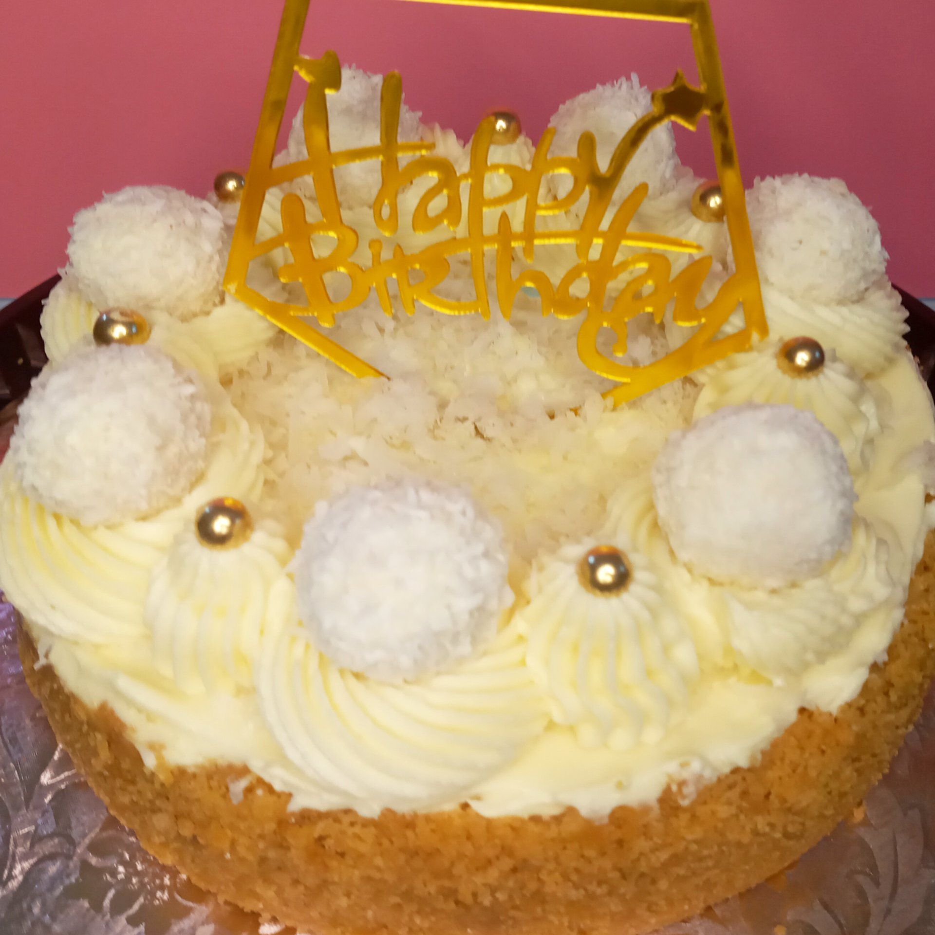 A cake with white frosting and a yellow happy birthday topper