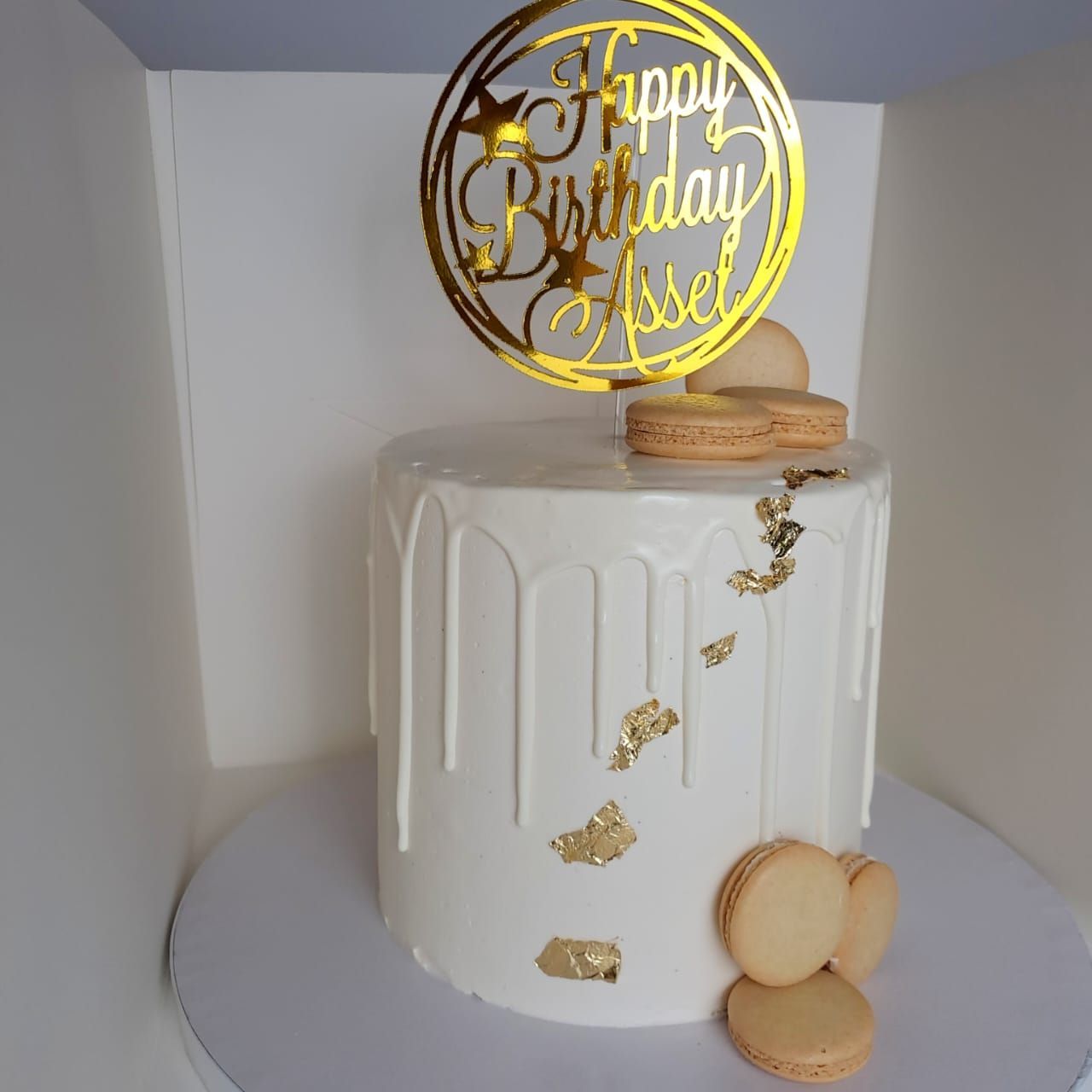 A white cake with a gold happy birthday topper