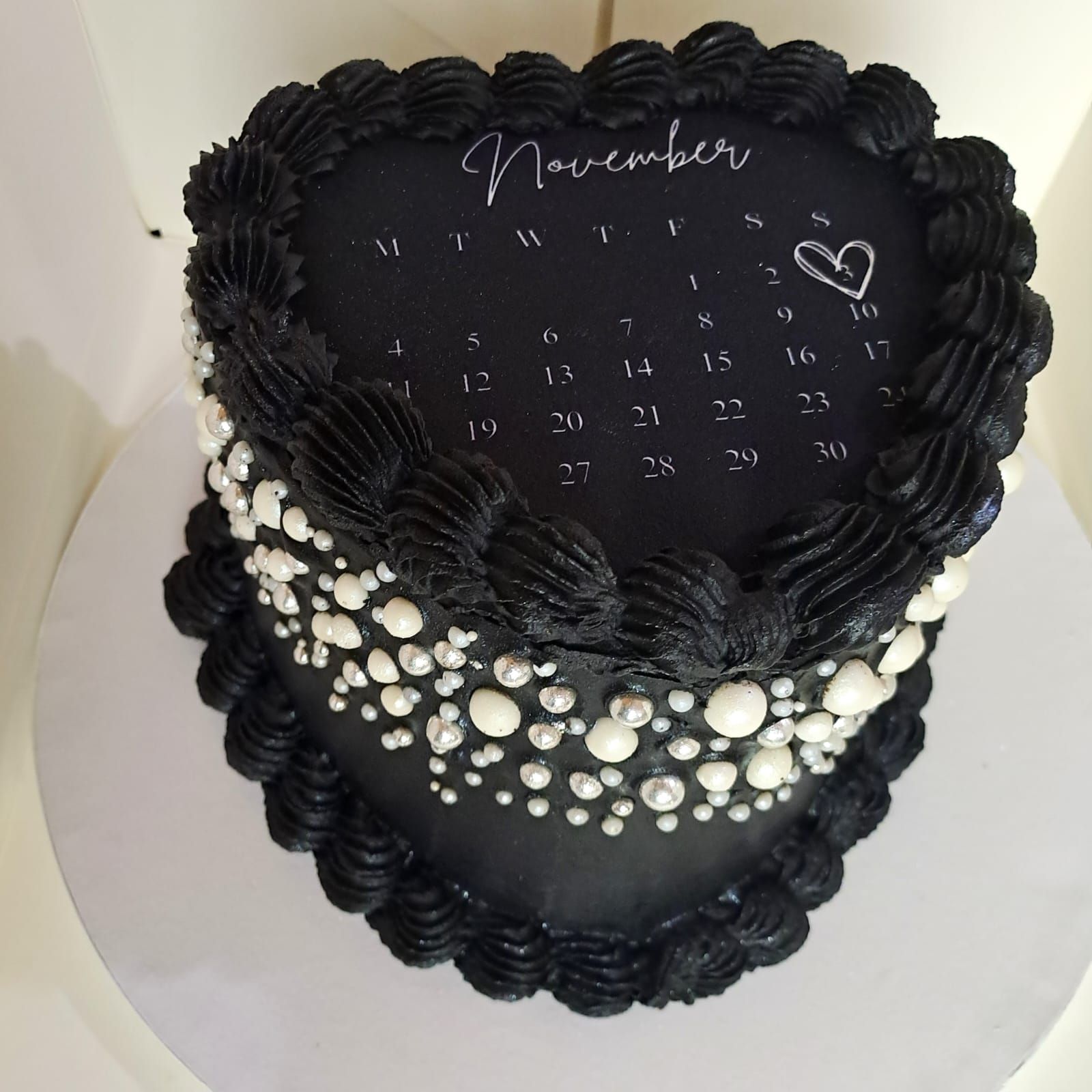 A black heart shaped cake with a calendar on it