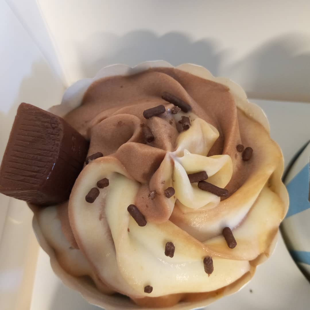 A close up of a cupcake with chocolate frosting and sprinkles