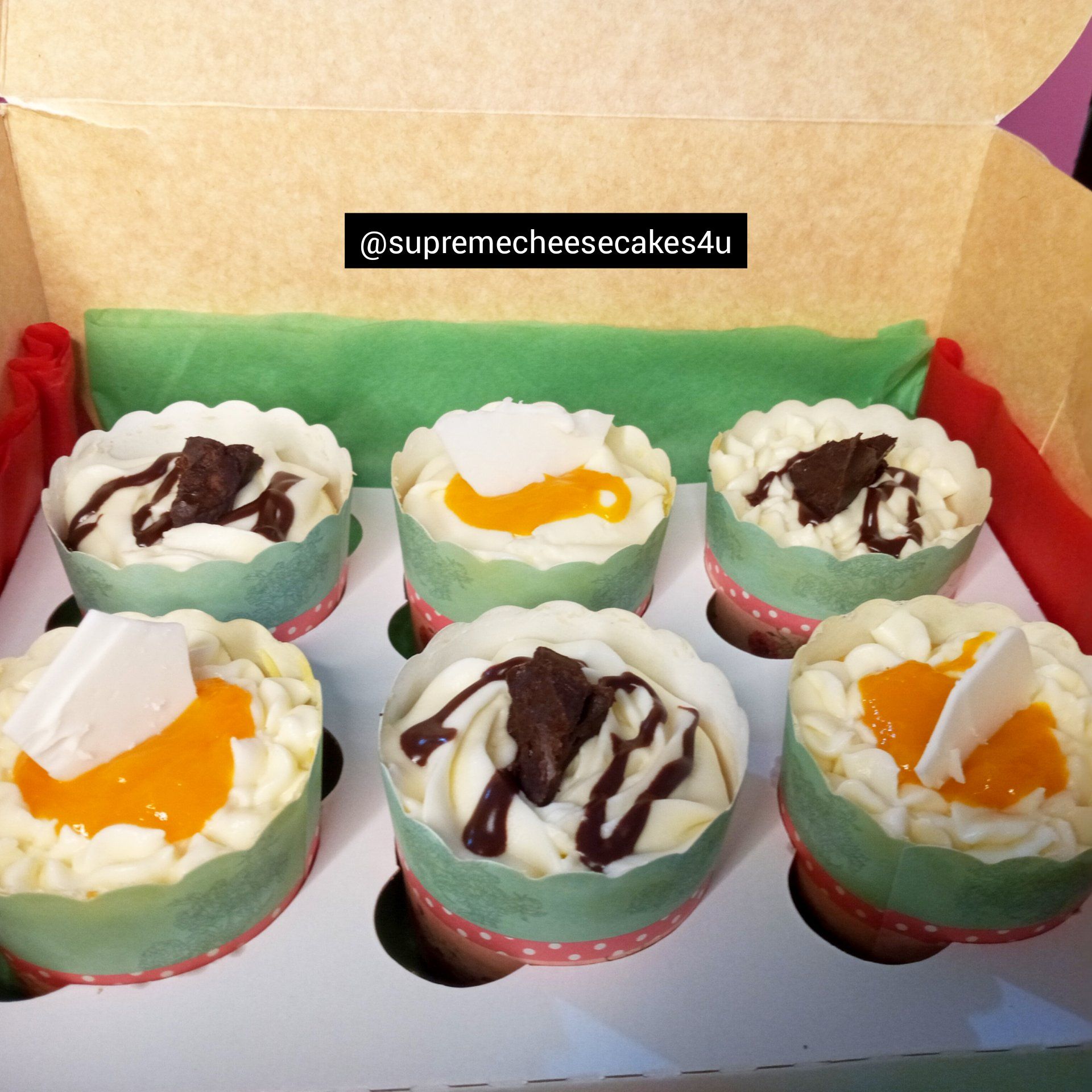 A box of cupcakes with different toppings is labeled @ aunamecheesecakes4u