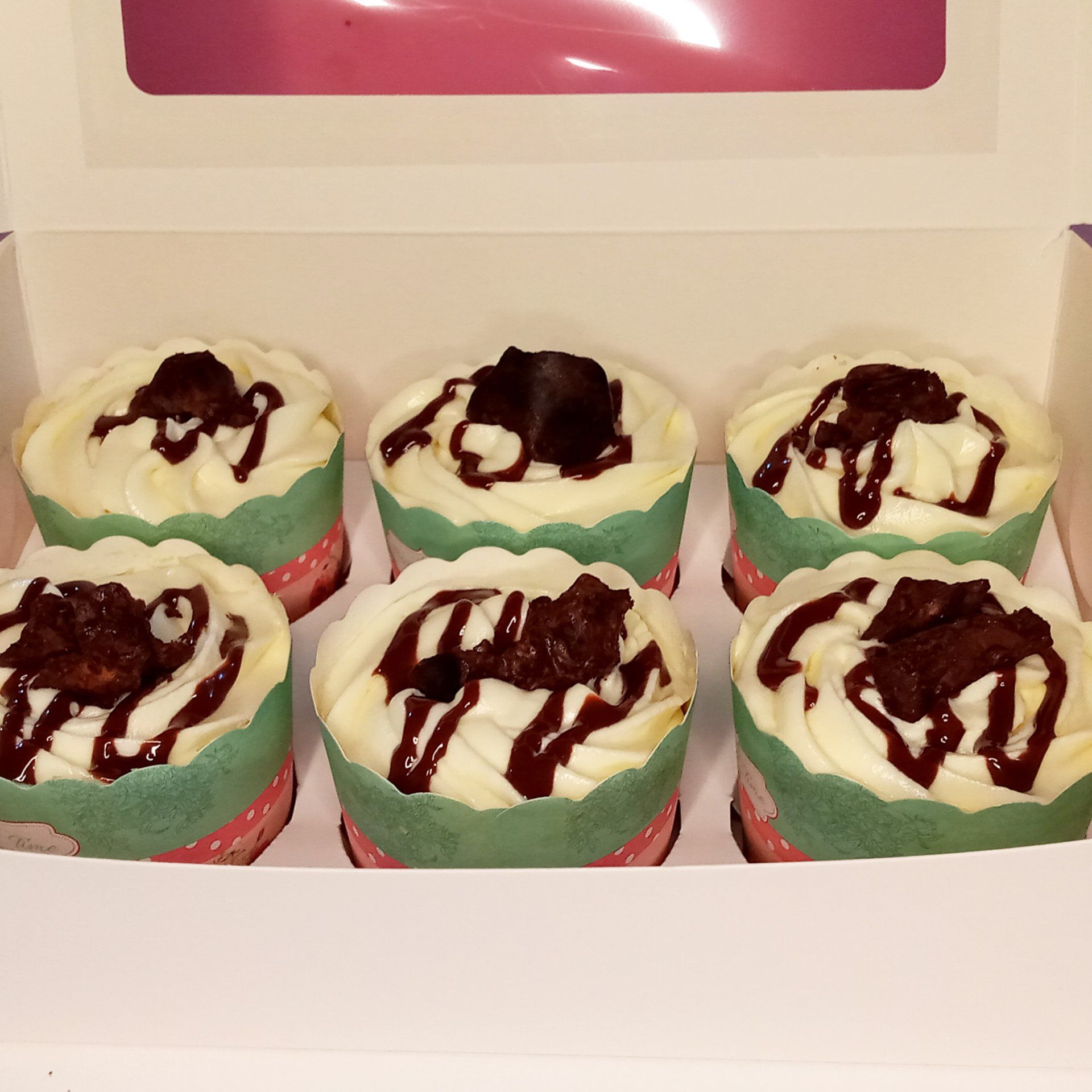 A box of cupcakes with chocolate frosting on them