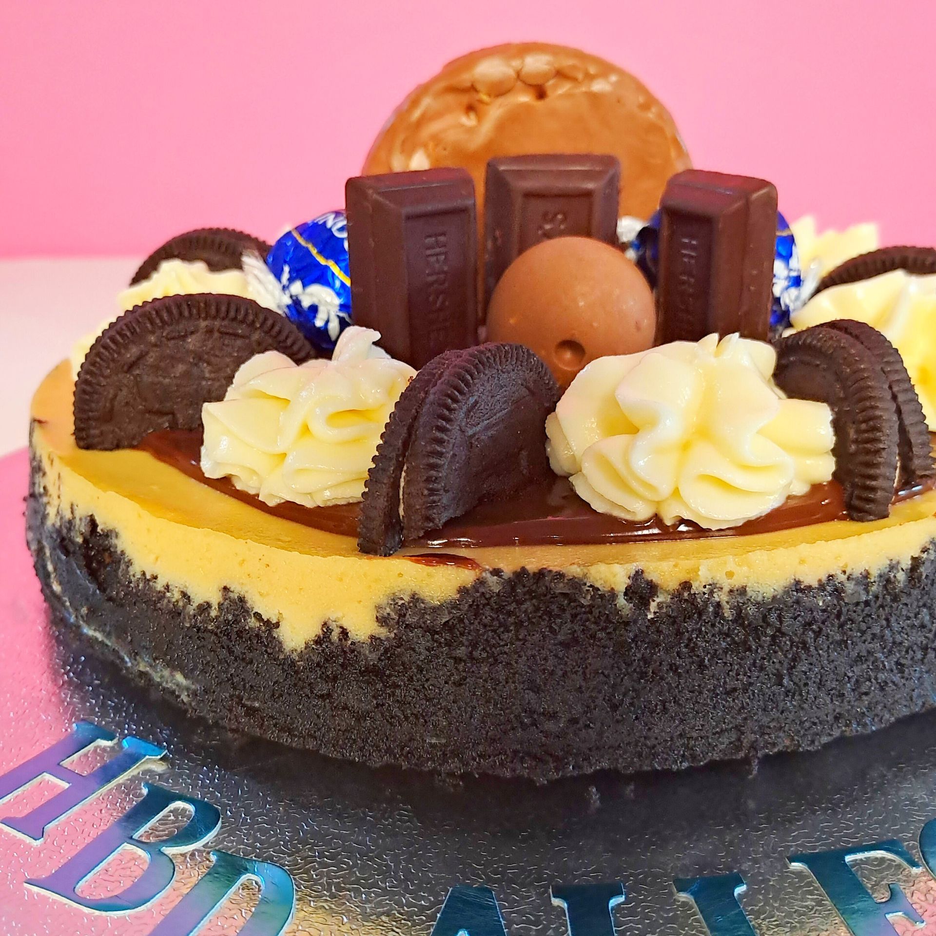 A cheesecake with oreos and hershey bars on top