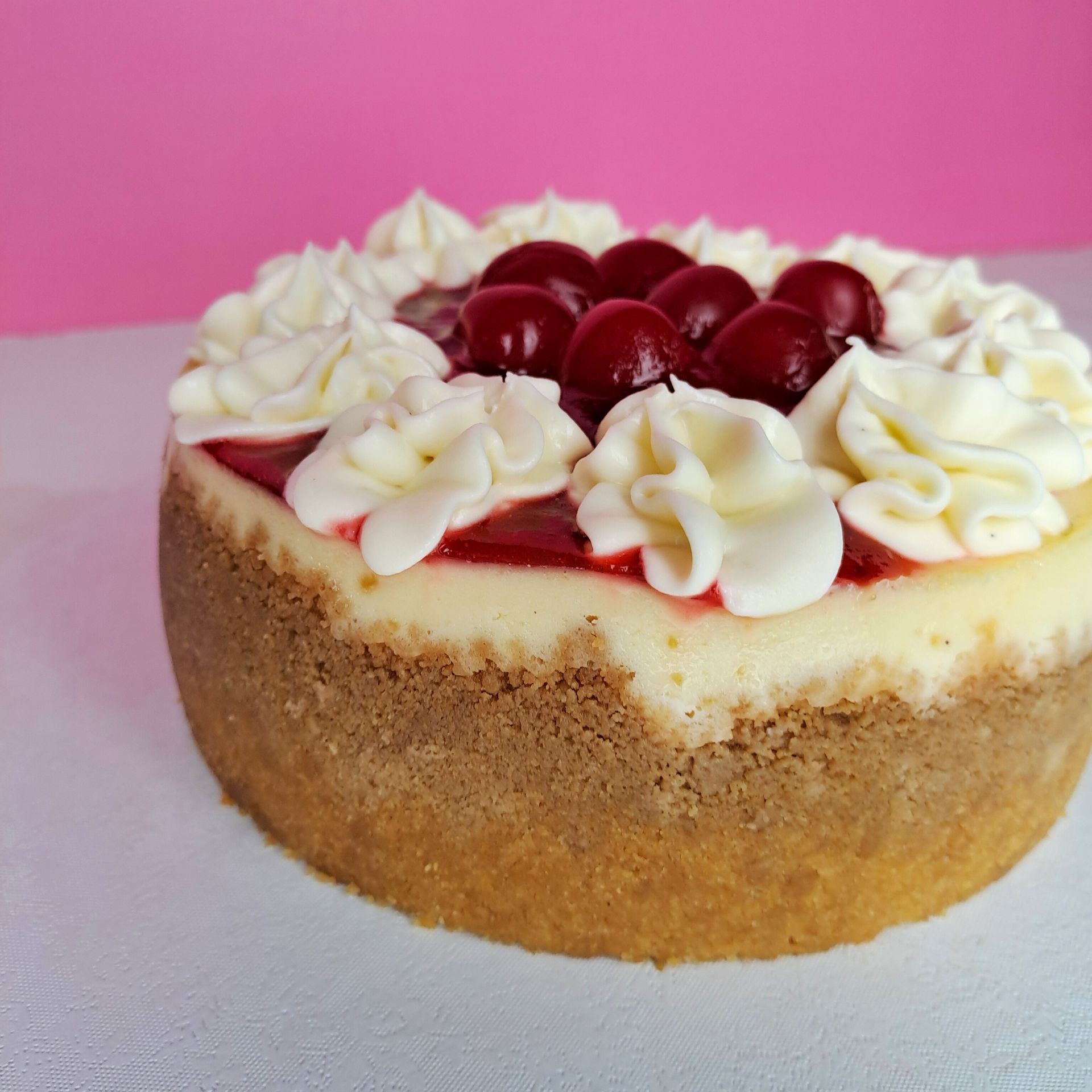 A cheesecake with whipped cream and cherries on top
