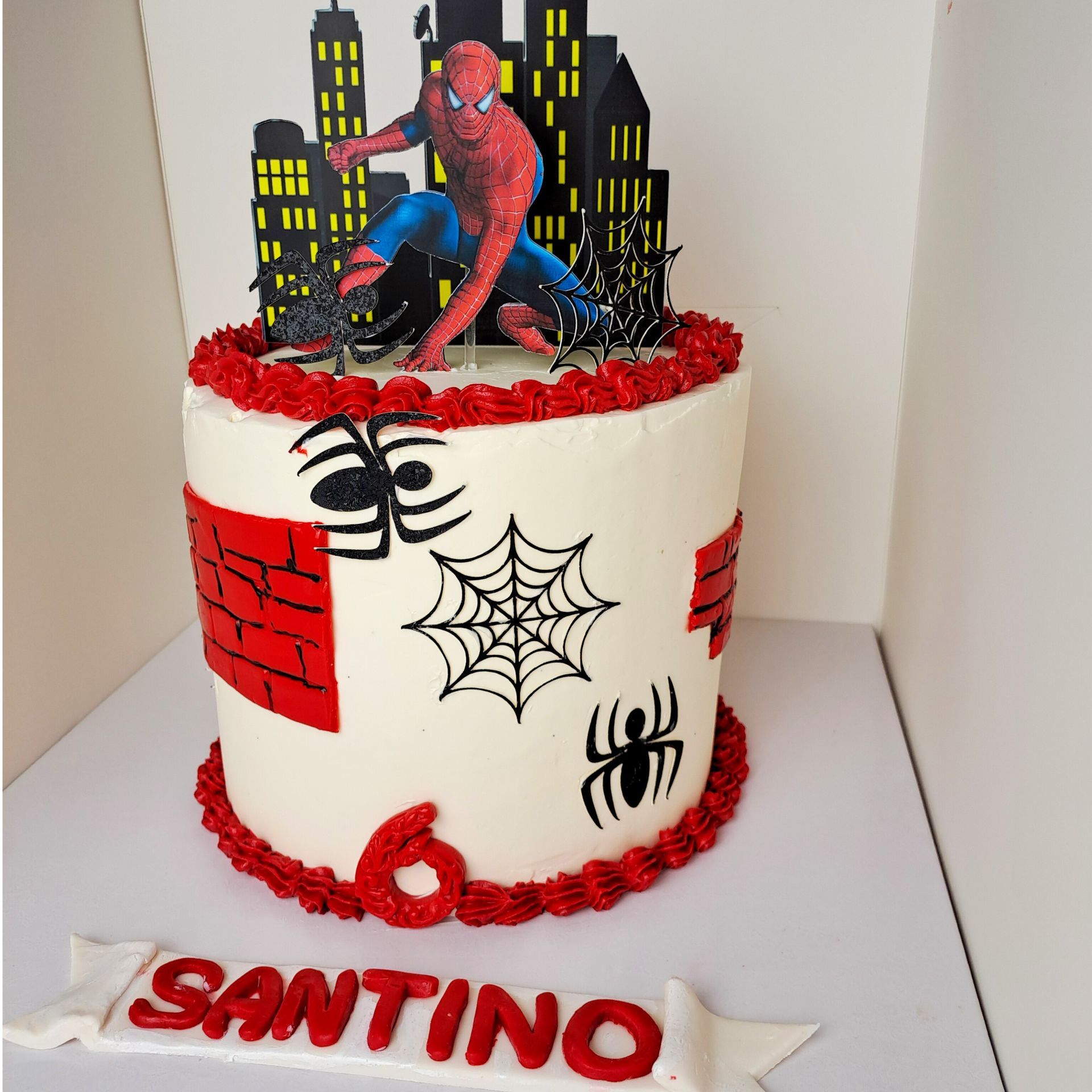A spiderman cake with the name santino on it