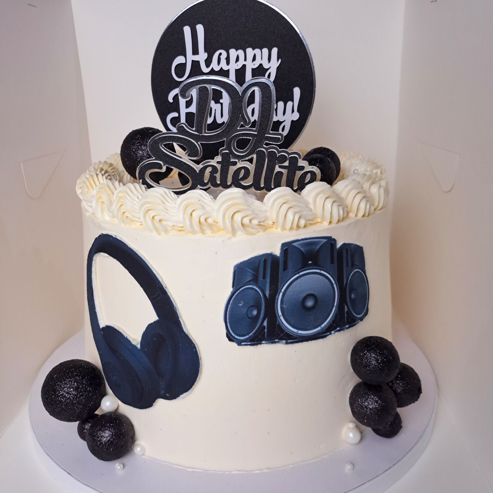A birthday cake with headphones and speakers on it
