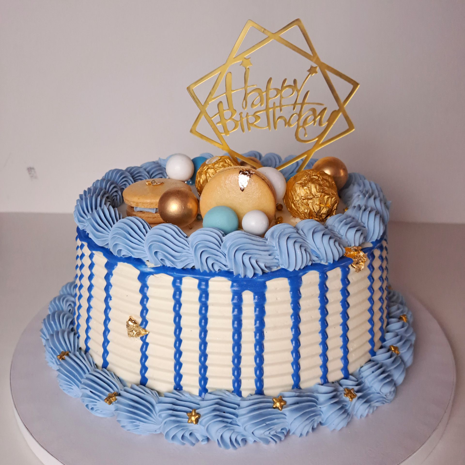 A blue and white birthday cake with a happy birthday topper