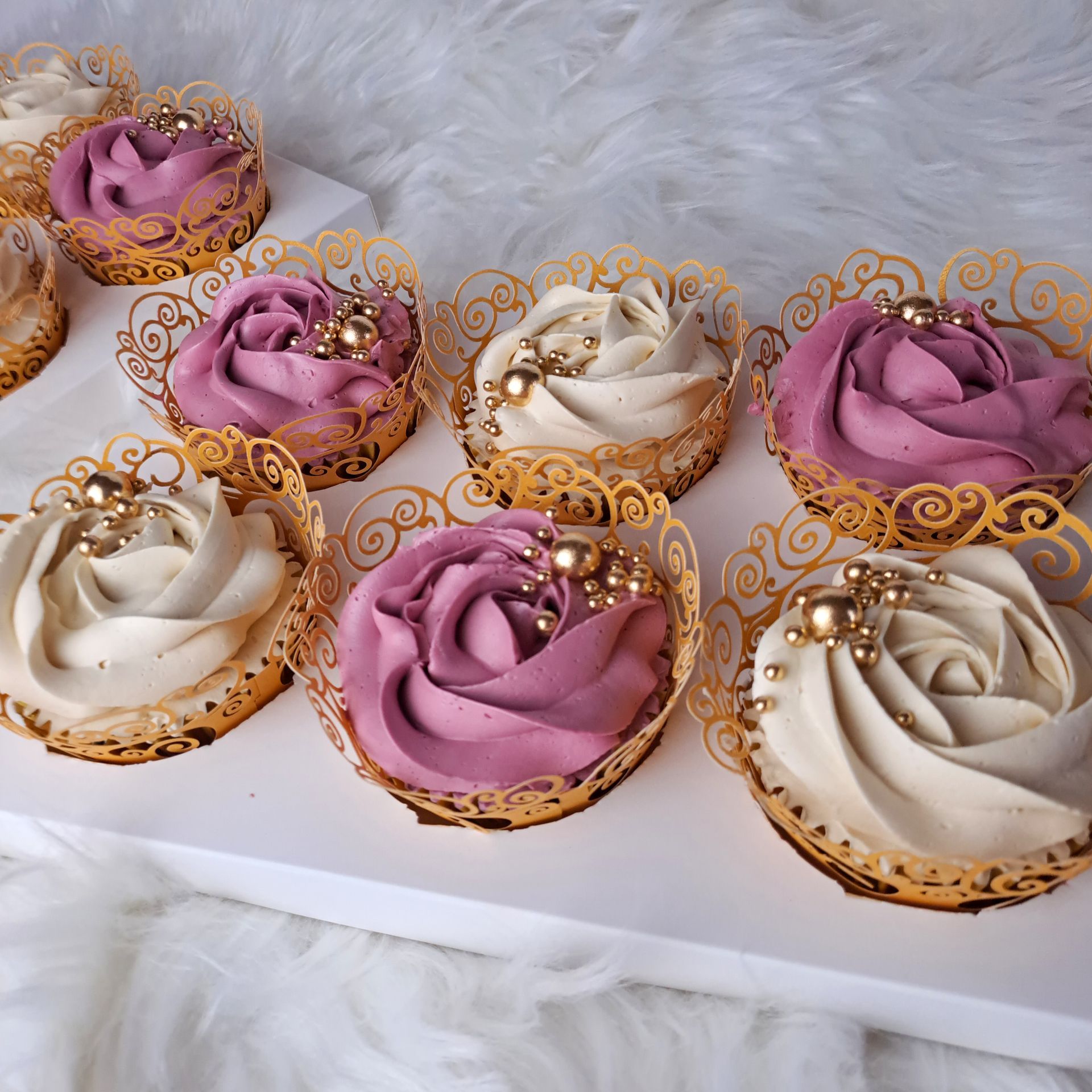 A box of cupcakes with purple and white frosting