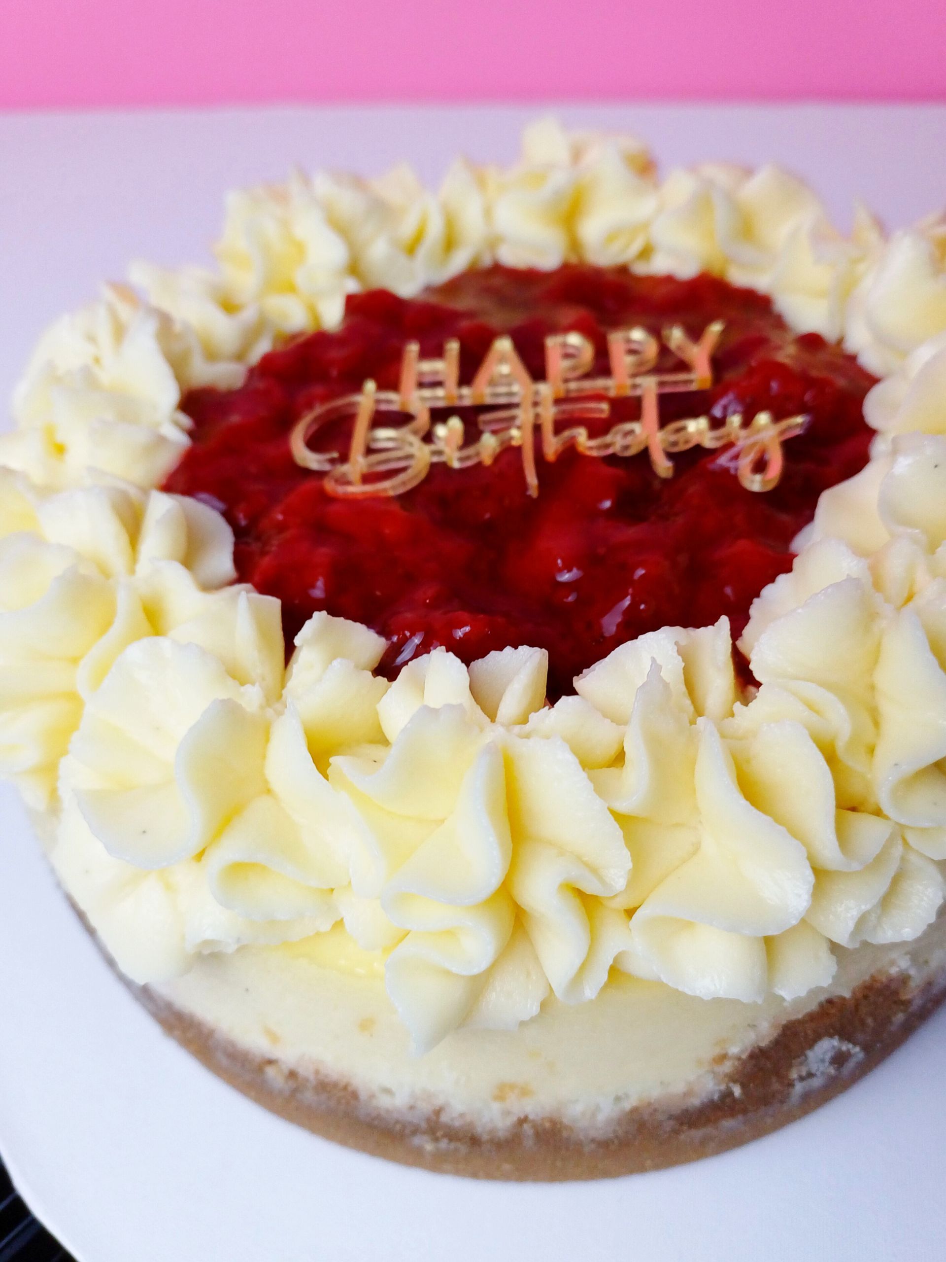 A circular cheesecake topped with a red fruit glaze and a 