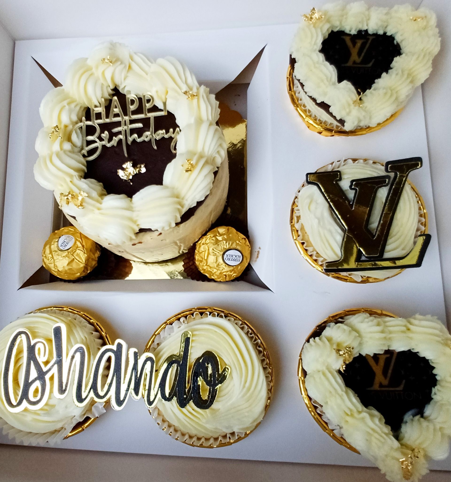 A white box holds a birthday cake, two heart-shaped cakes, three cupcakes, and two Ferrero Rocher chocolates.