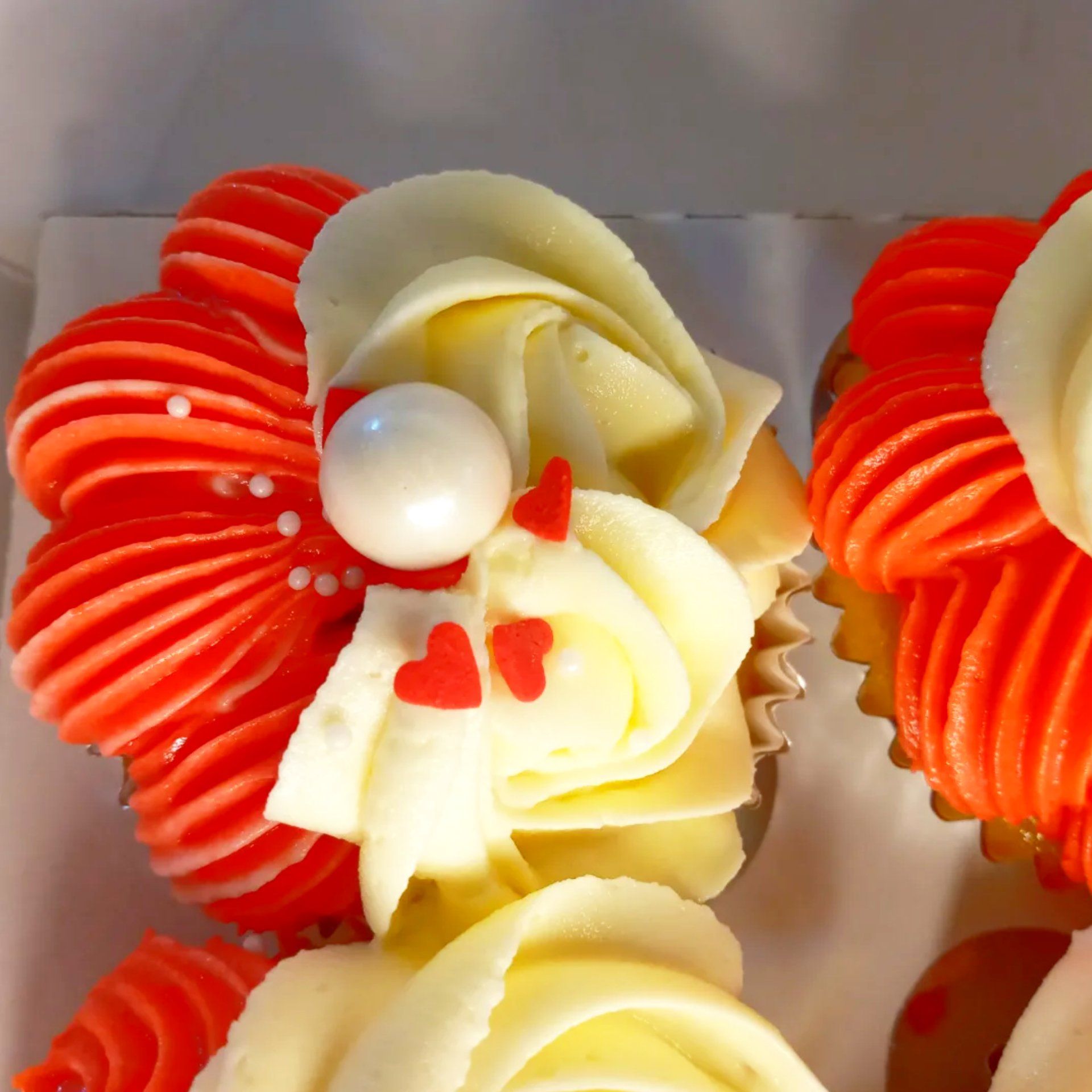 A box of cupcakes with red and white frosting