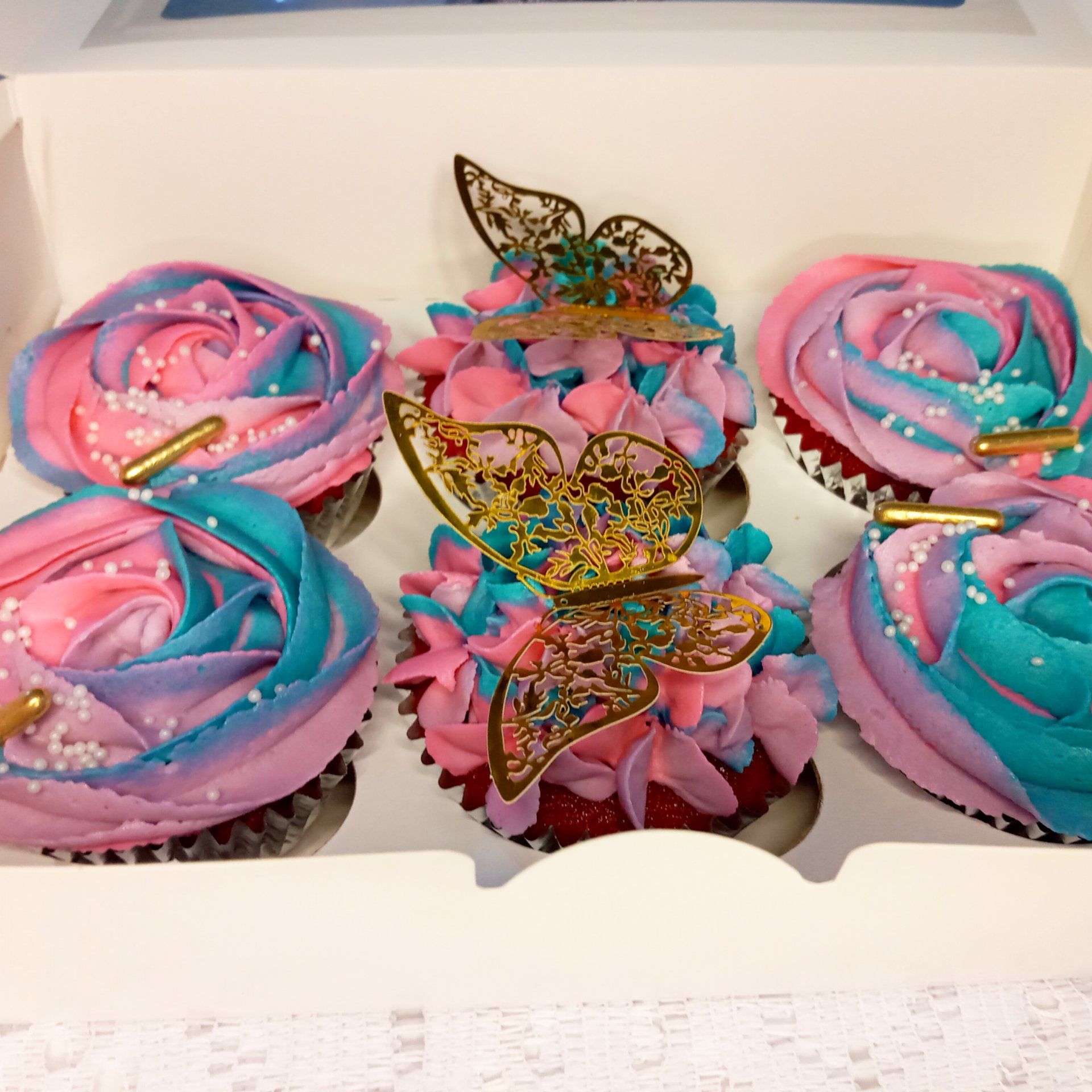 A box of pink and blue cupcakes with butterflies on them