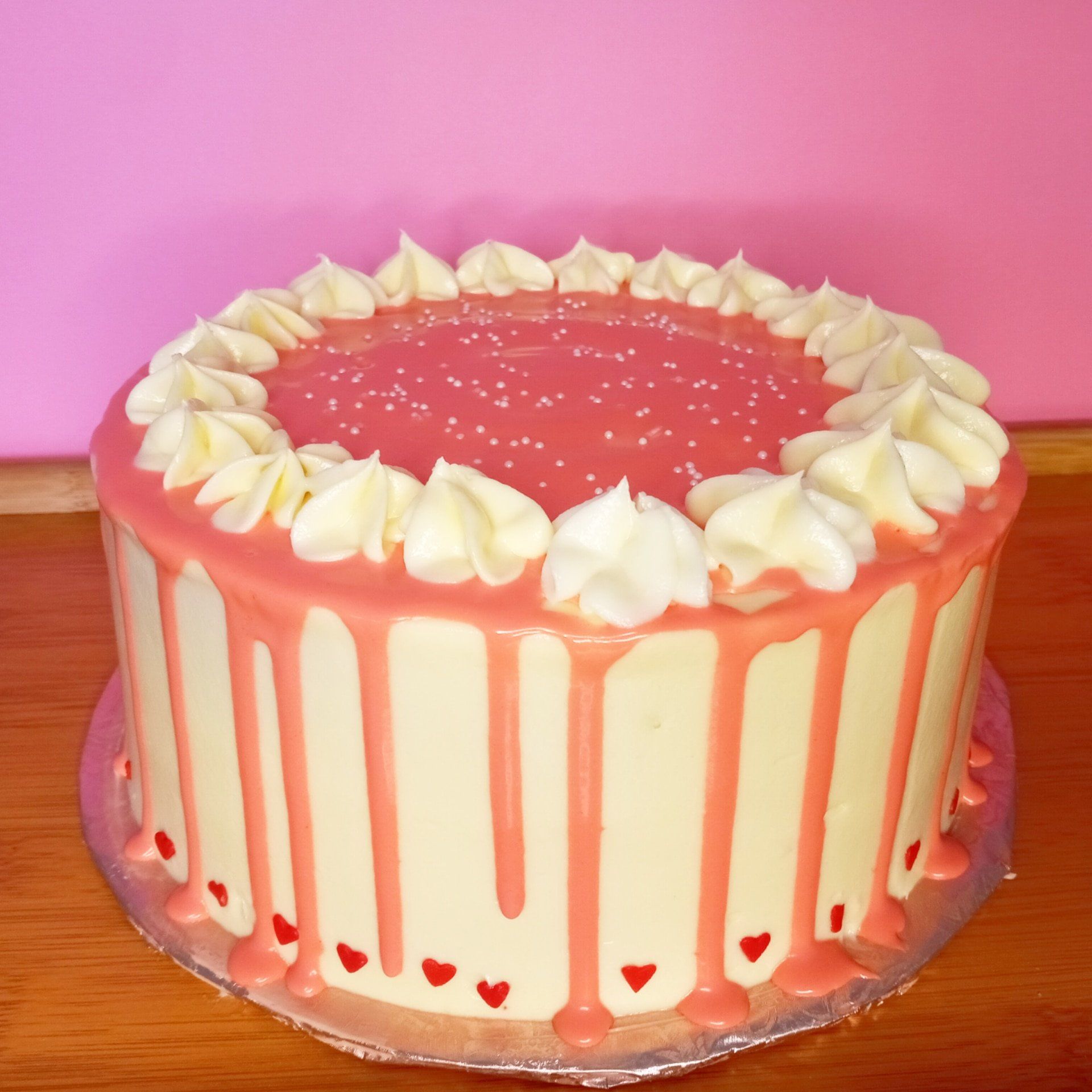 A pink and white cake with hearts on it