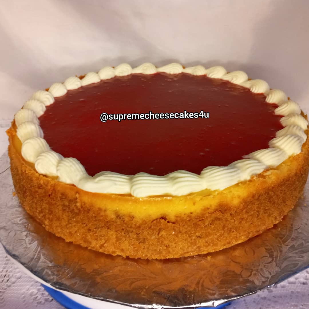 A cheesecake with raspberry sauce and whipped cream on top