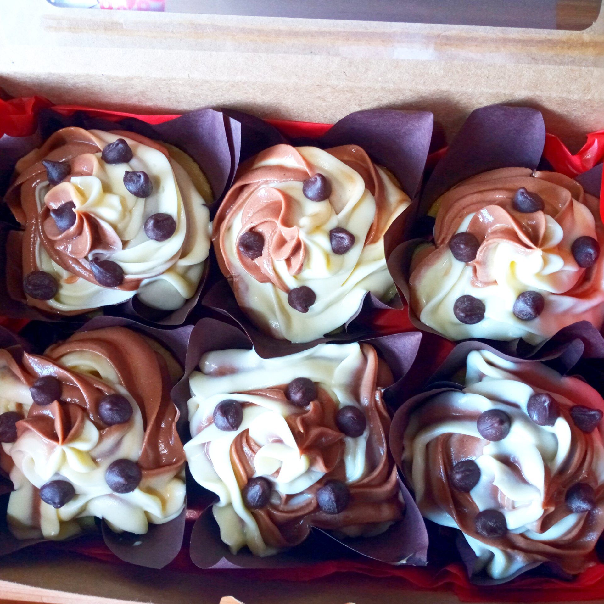 A box of cupcakes with chocolate chips on top