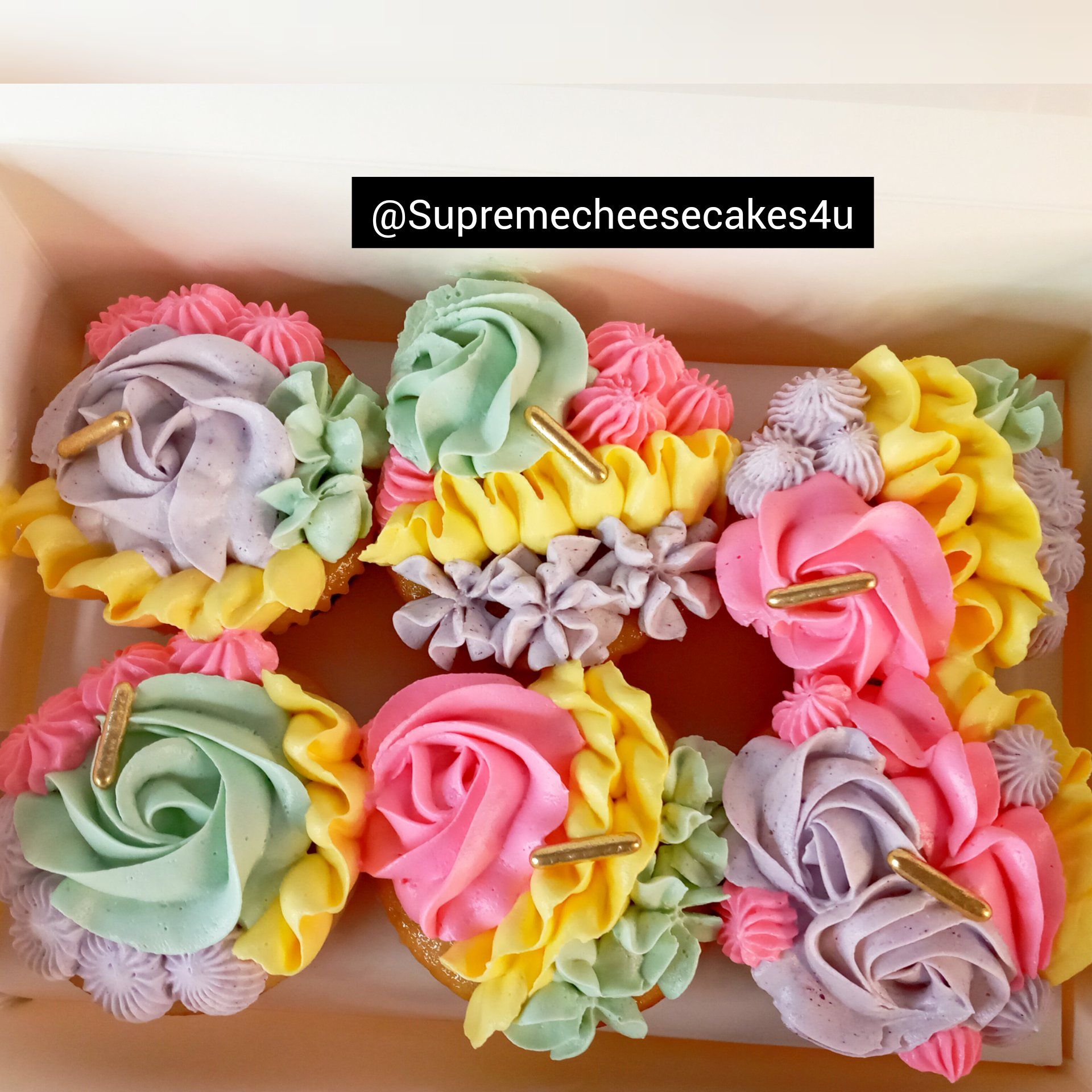 A box of cupcakes decorated with different colors of frosting