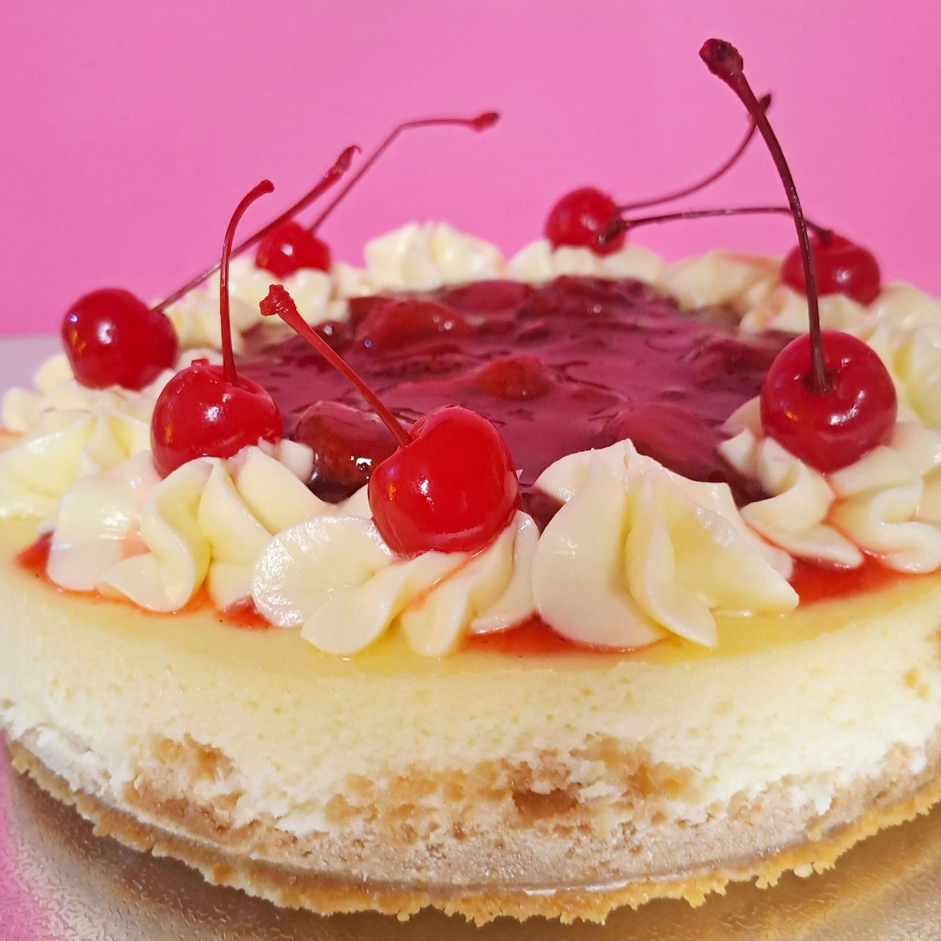 A cheesecake with whipped cream and cherries on top