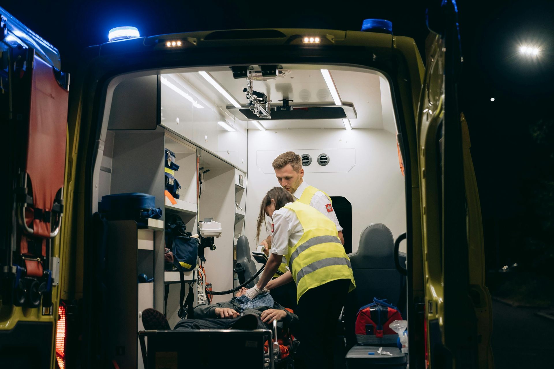 Ambulance interior at night, medics attending to a patient on a stretcher.