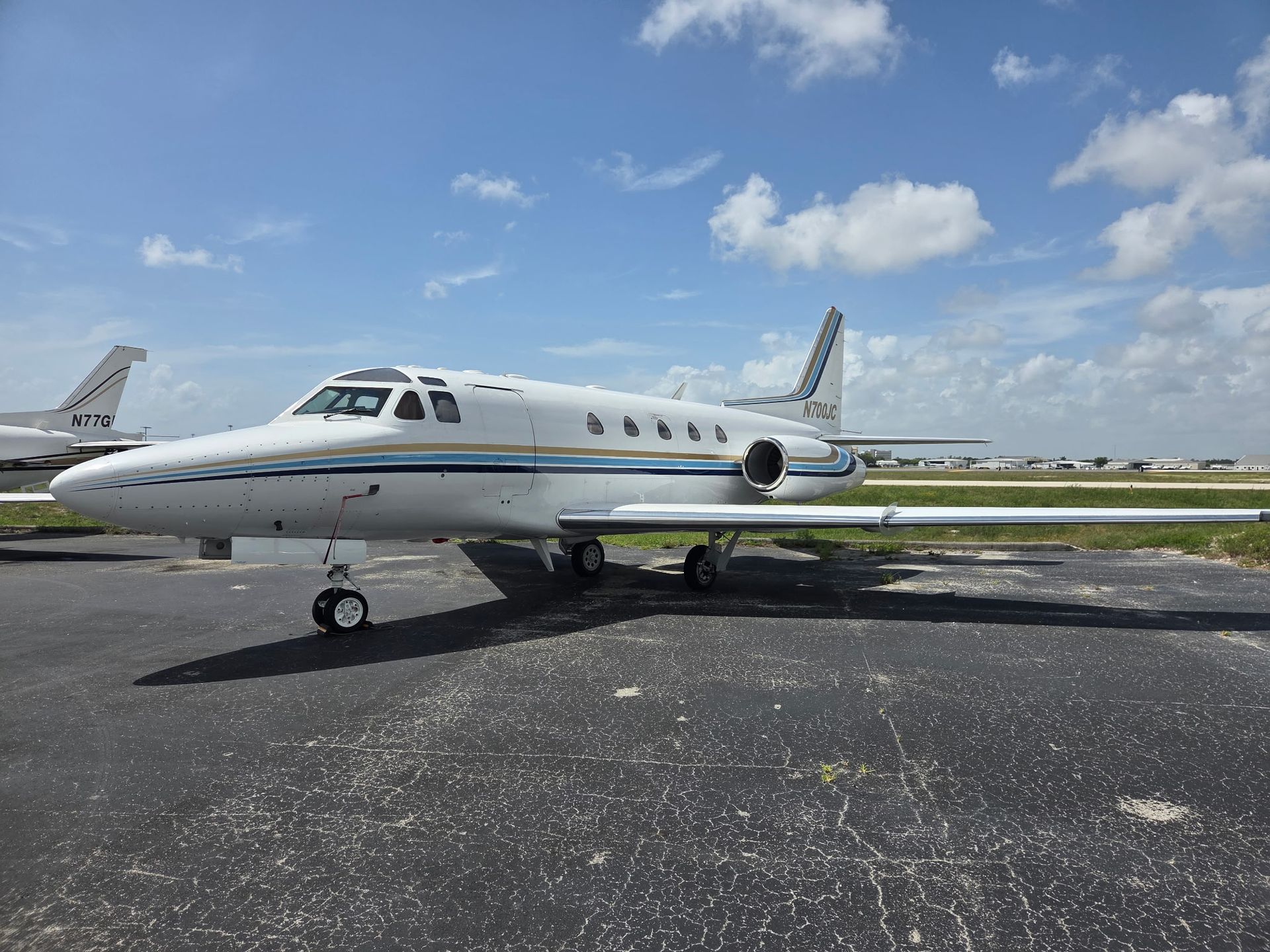 A small private jet is parked on the tarmac at an airport.