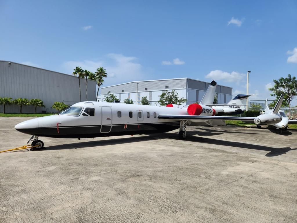 A small private jet is parked on the tarmac in front of a building.