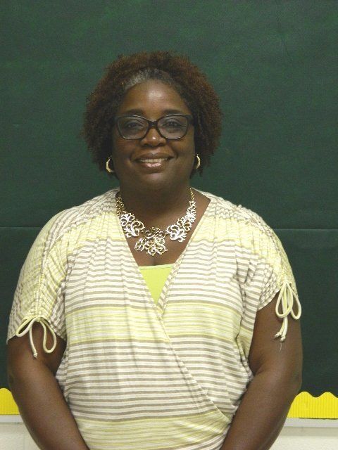 A woman wearing glasses and a striped shirt smiles for the camera