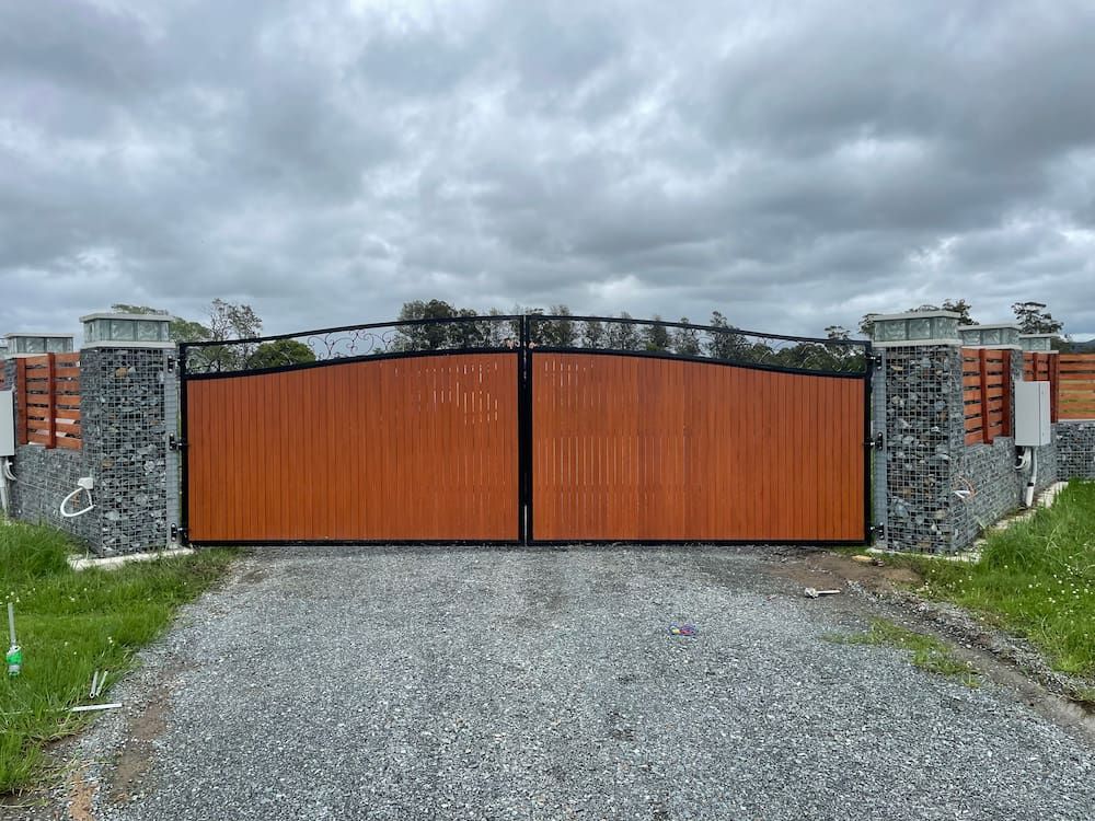 A Wooden Gate is Sitting on the Side of a Gravel Road — Riverside Aluminium & Stainless in Taree, NSW