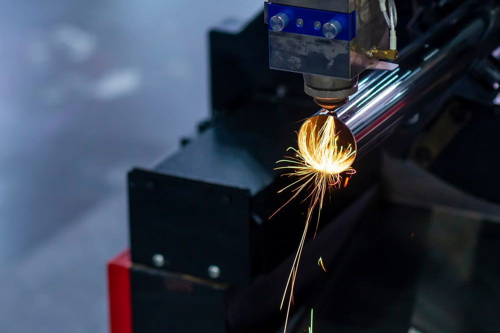 A Machine is Cutting a Metal Pipe With Sparks Coming Out of It — Riverside Aluminium & Stainless in Coolongolook, NSW