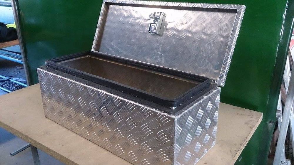 A Metal Box With the Lid Open is Sitting on a Wooden Table — Riverside Aluminium & Stainless in Taree, NSW