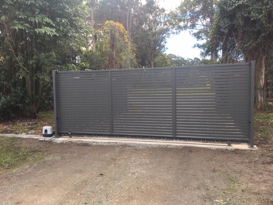 A Sliding Gate is Sitting in the Middle of a Dirt Road — Riverside Aluminium & Stainless in Forster, NSW