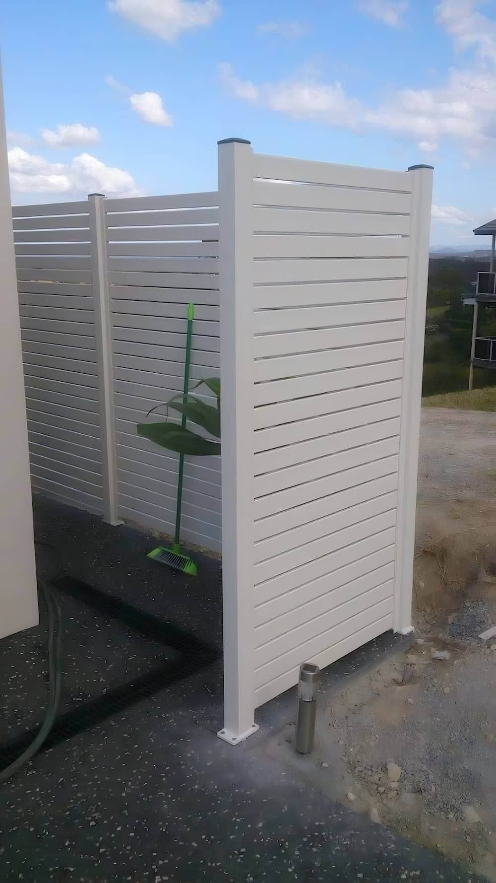 A White Privacy Fence is Sitting on the Side of a Road — Riverside Aluminium & Stainless in Forster, NSW