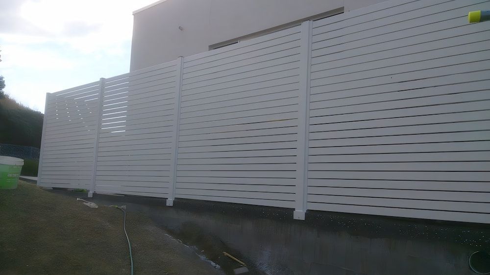 A White Privacy Fence is Sitting on the Side of a Building — Riverside Aluminium & Stainless in Forster, NSW