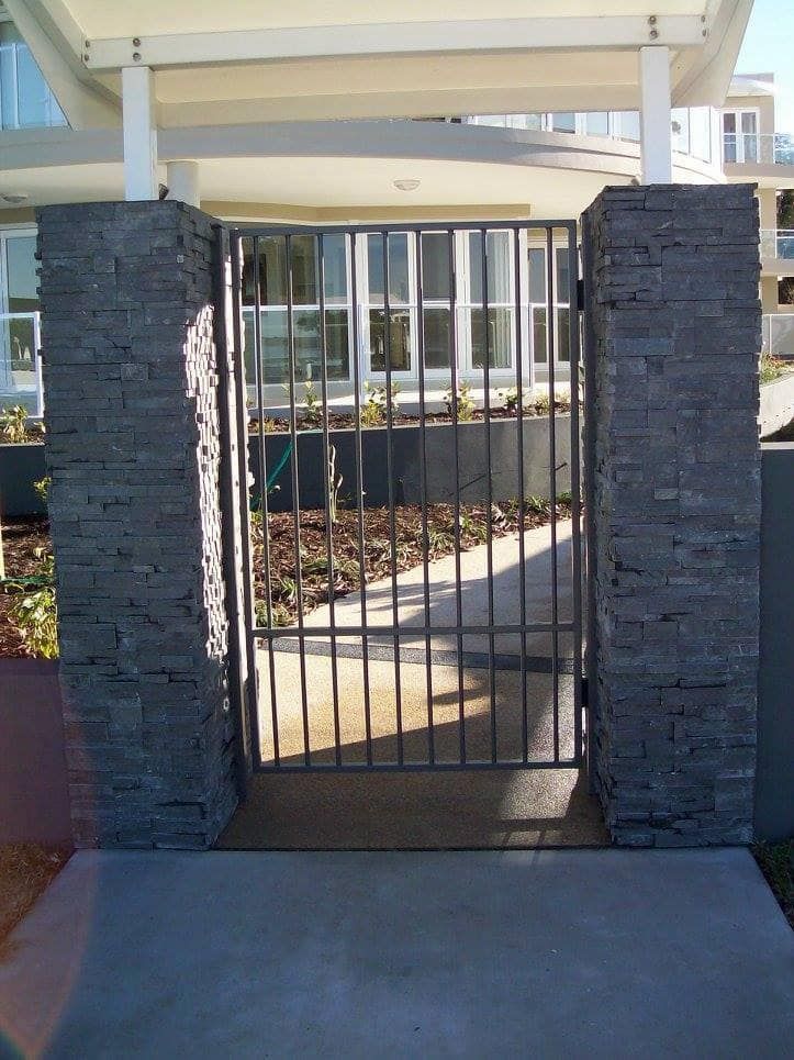 A Metal Gate Between Two Brick Pillars in Front of a House — Riverside Aluminium & Stainless in Coolongolook, NSW