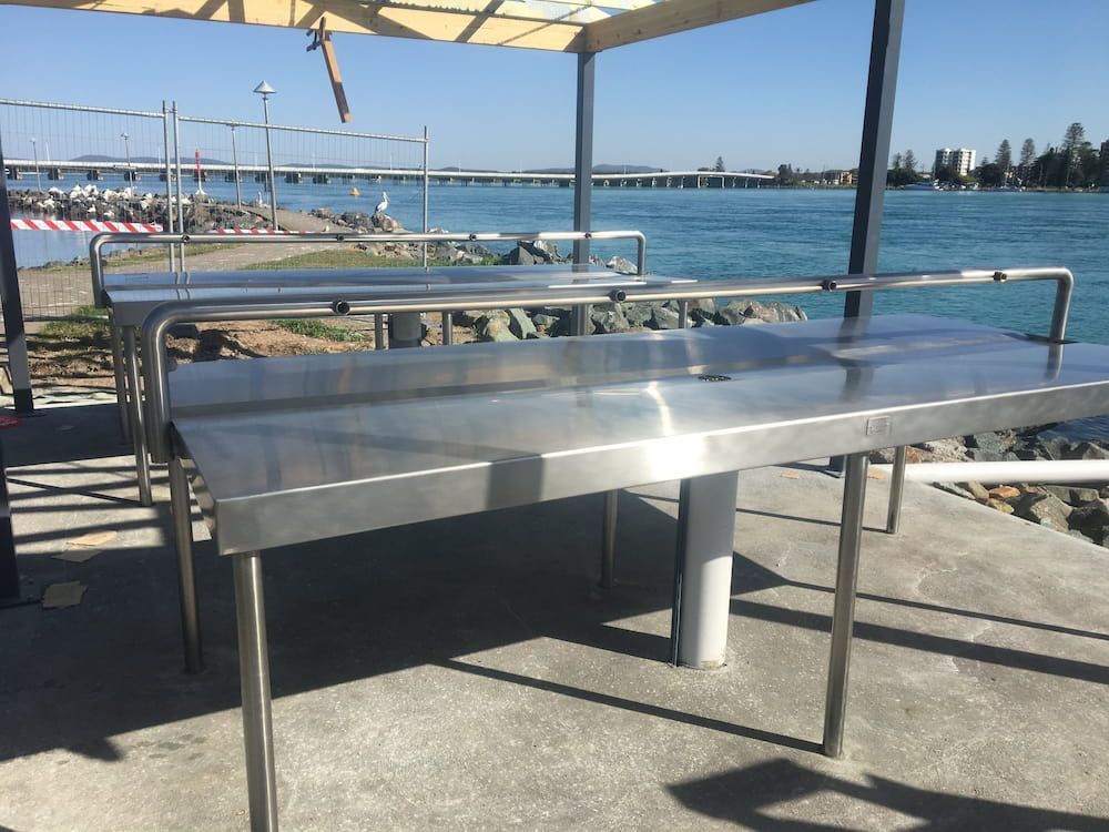 A Stainless Steel Table Sits in Front of a Body of Water — Riverside Aluminium & Stainless in Forster, NSW