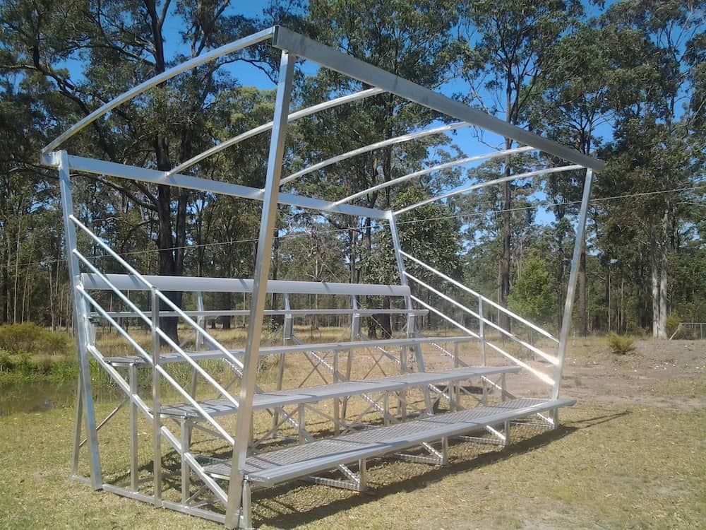 A Metal Bleacher is Sitting in the Middle of a Field With Trees in the Background — Riverside Aluminium & Stainless in Coolongolook, NSW