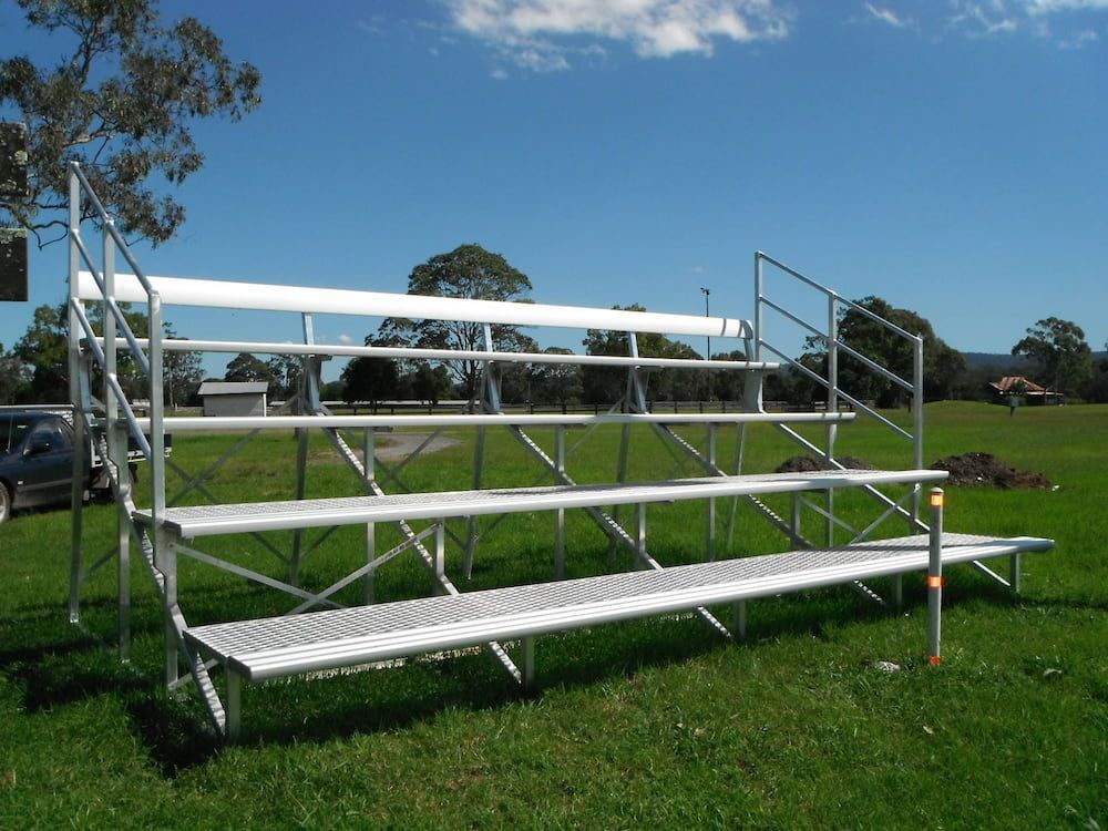 A Bleacher is Sitting in the Middle of a Grassy Field — Riverside Aluminium & Stainless in Forster, NSW
