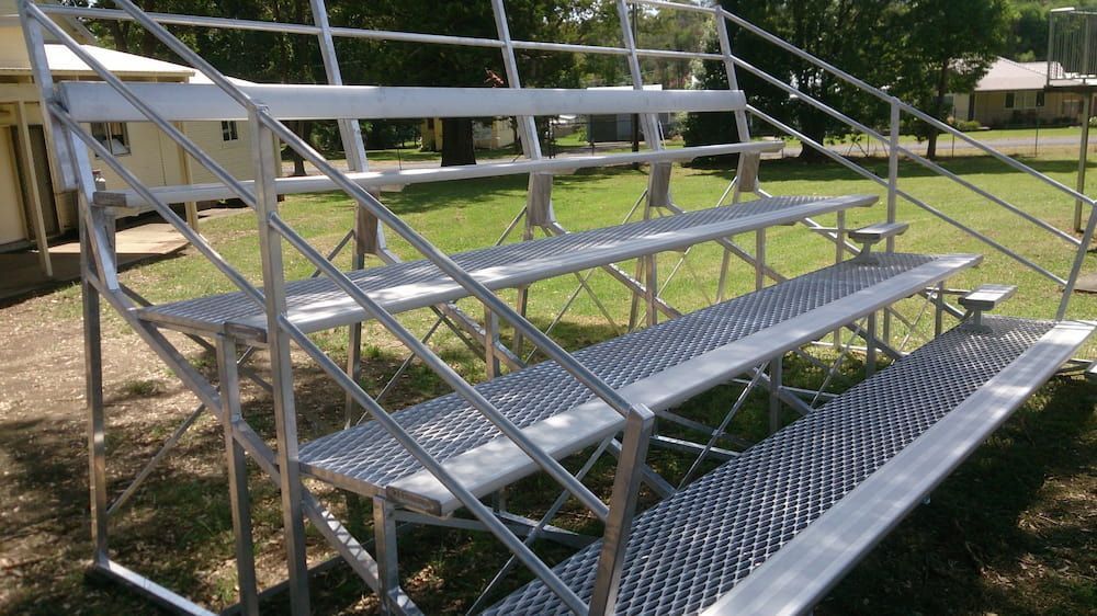 A Metal Bleacher is Sitting in the Grass in Front of a House — Riverside Aluminium & Stainless in Forster, NSW