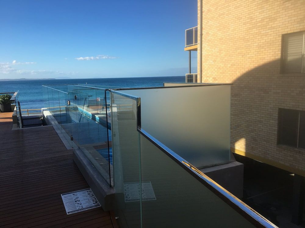 A Balcony With a Glass Railing Overlooking the Ocean — Riverside Aluminium & Stainless in Forster, NSW