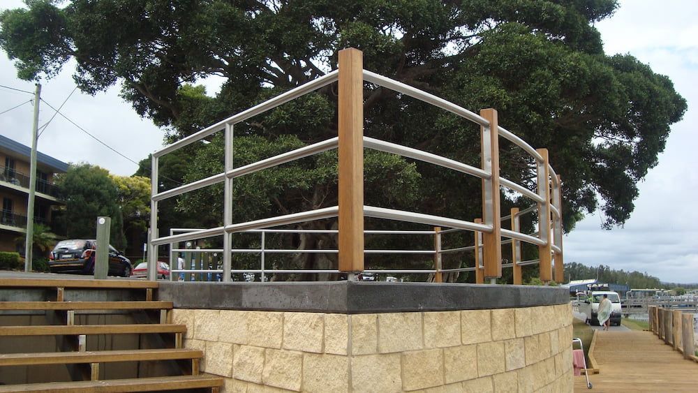 A Brick Wall With a Metal Railing and a Tree in the Background  — Riverside Aluminium & Stainless in Forster, NSW