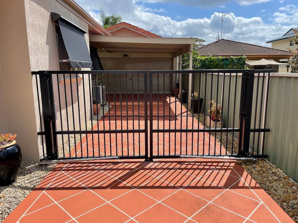 A Black Gate is Sitting in Front of a House — Riverside Aluminium & Stainless in Harrington, NSW
