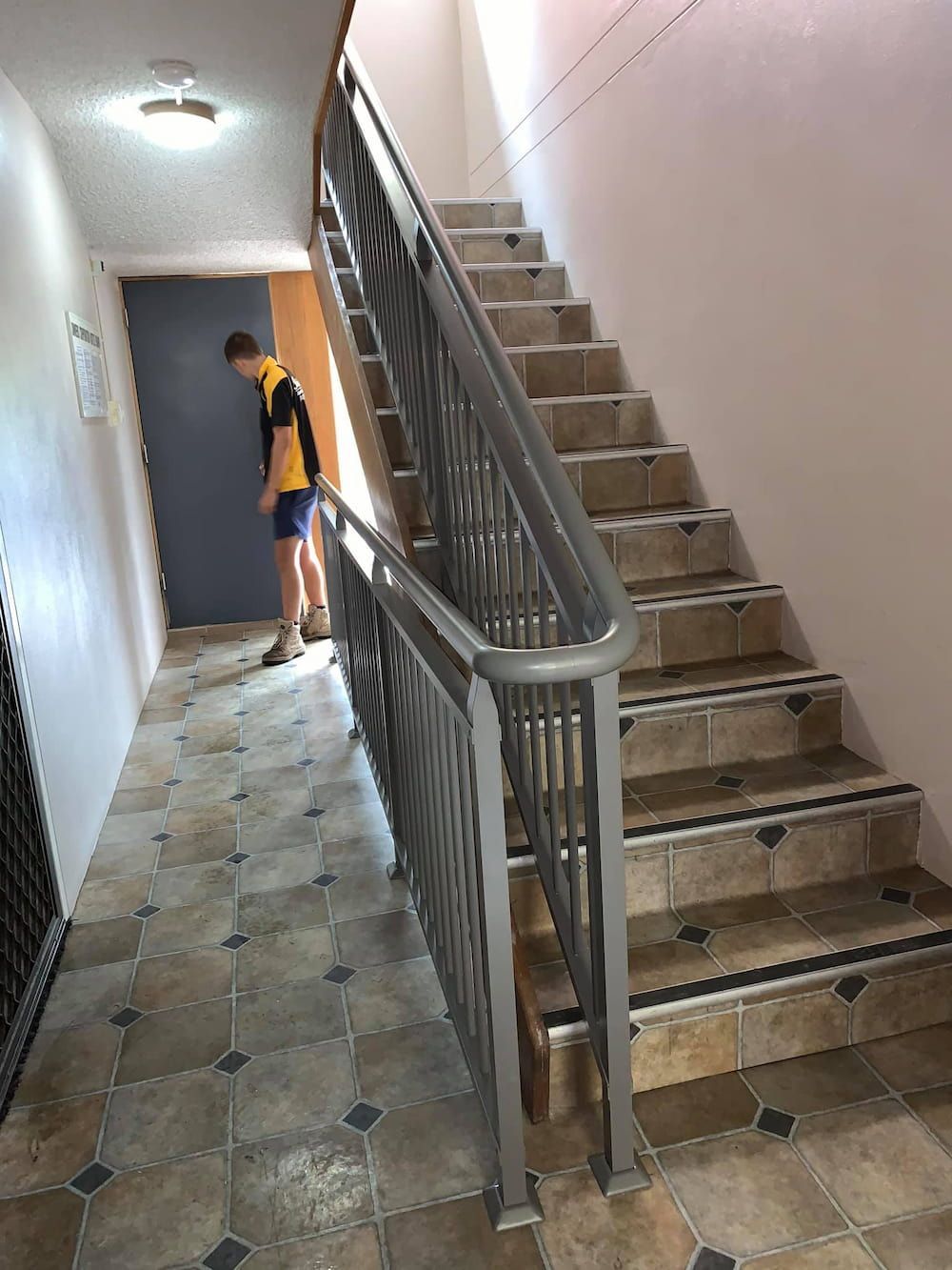 A Man is Standing in a Hallway Next to a Set of Stairs — Riverside Aluminium & Stainless in Harrington, NSW
