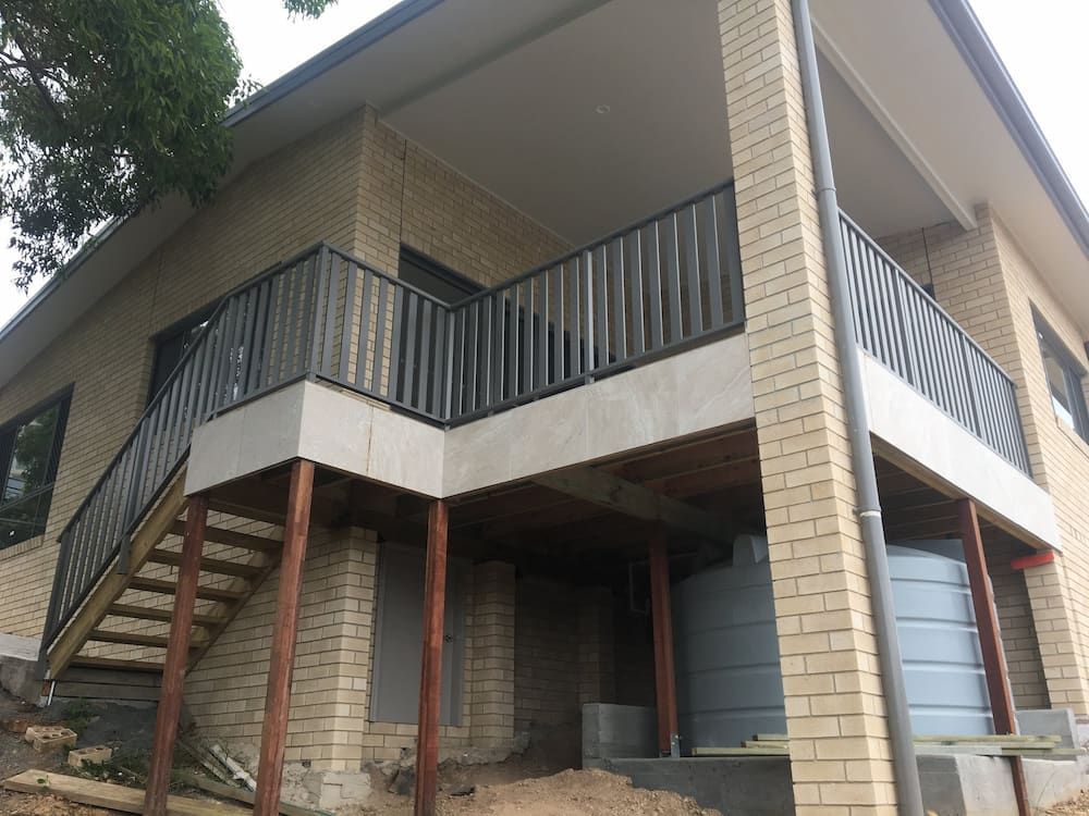 A brick house with a balcony and stairs — Riverside Aluminium & Stainless in Forster, NSW